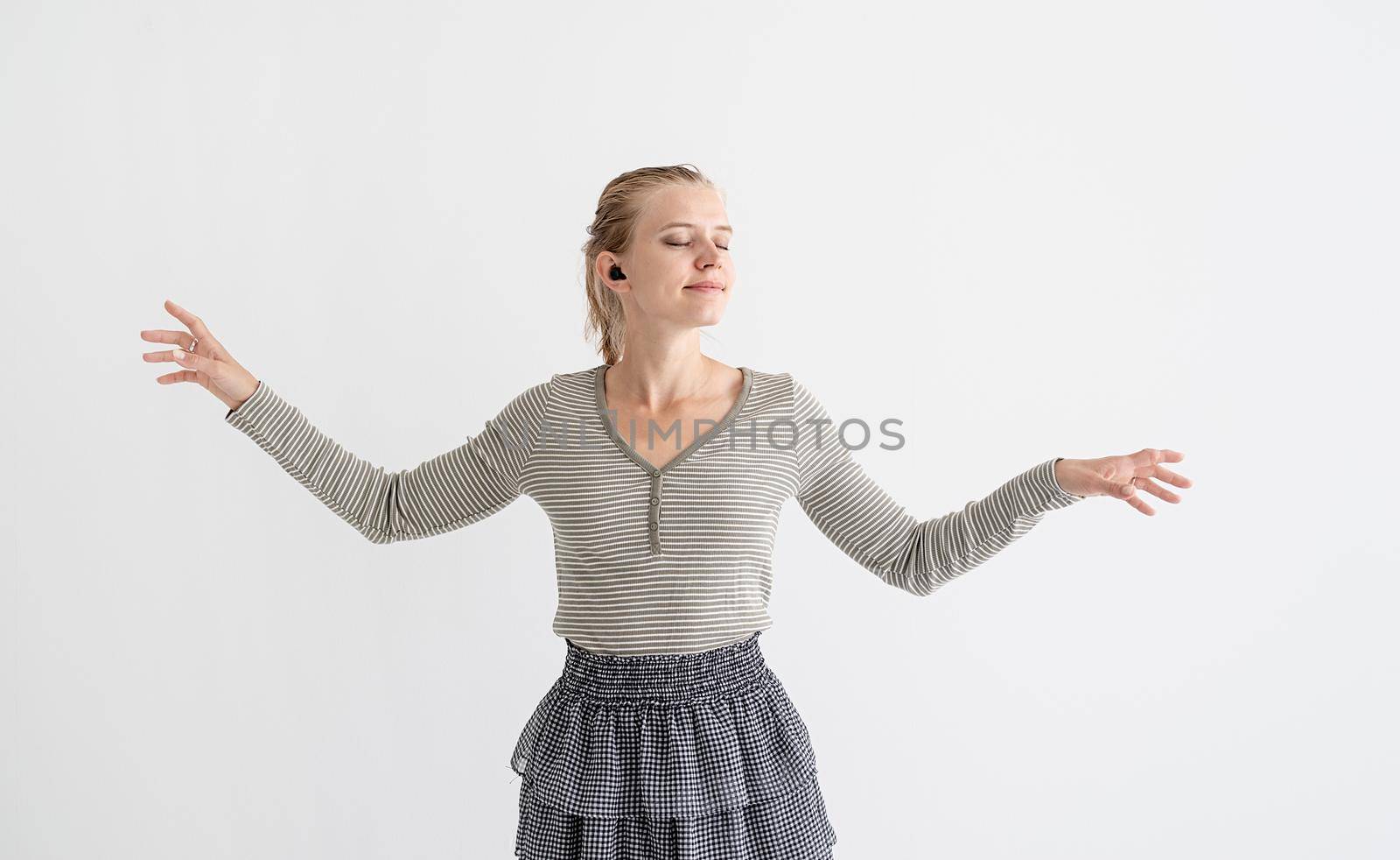 Music, isolation and leisure. Young woman holding wireless earbuds and dancing