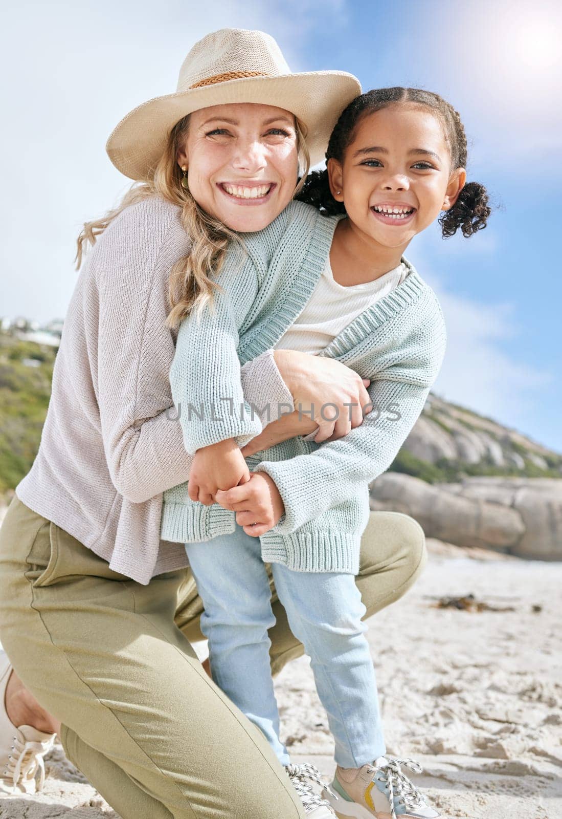 Hug, mother and child, together and on the beach, love and care, bonding in portrait for travel outdoor on the seaside. Happy, woman and girl, family and summer holiday, adventure and smile