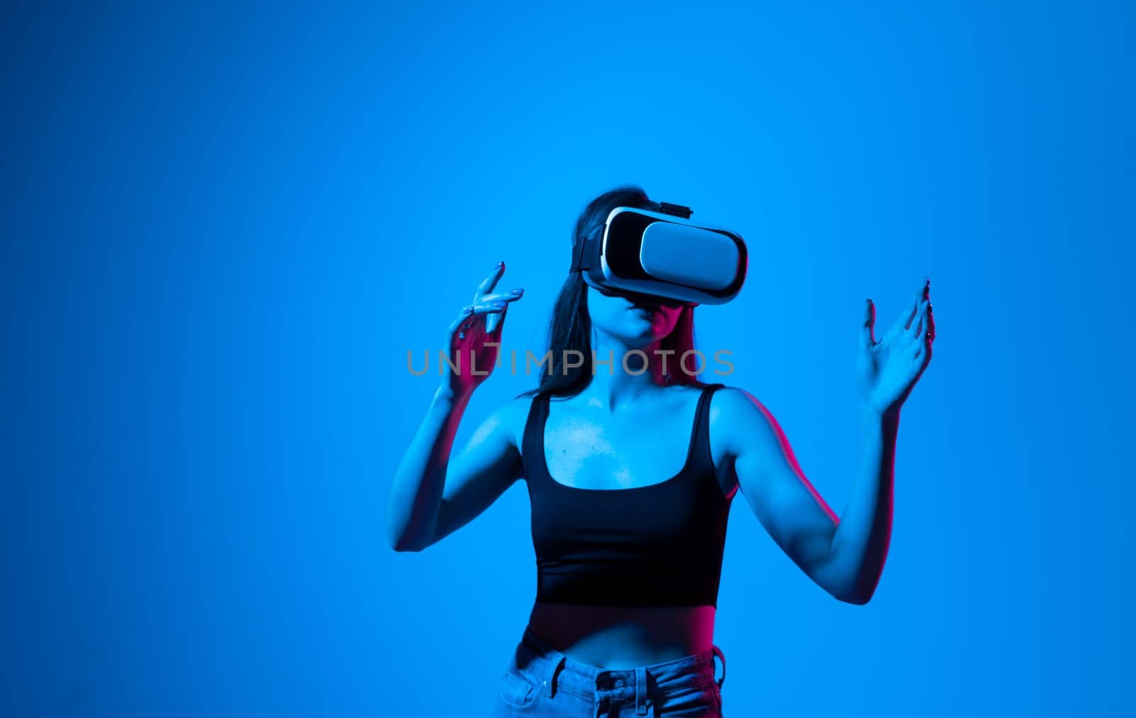 Portrait of young attractive brunette woman in a black top with a virtual reality goggles forehead. VR headset. Virtual reality concept. by vovsht