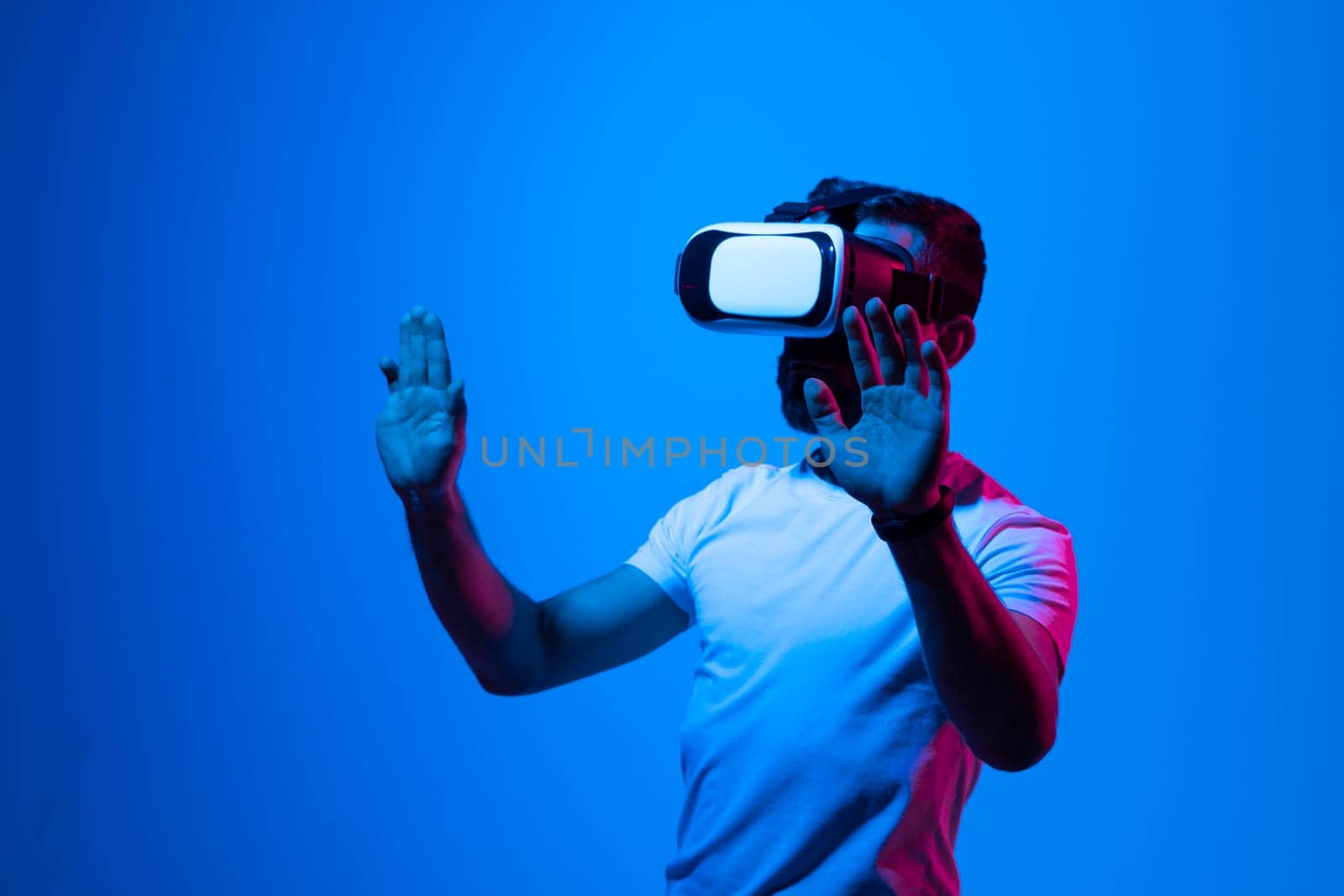 Bearded brunette man in white t-shirt wearing virtual reality goggle and immersing himself in VR multimedia. Future technology concept. by vovsht