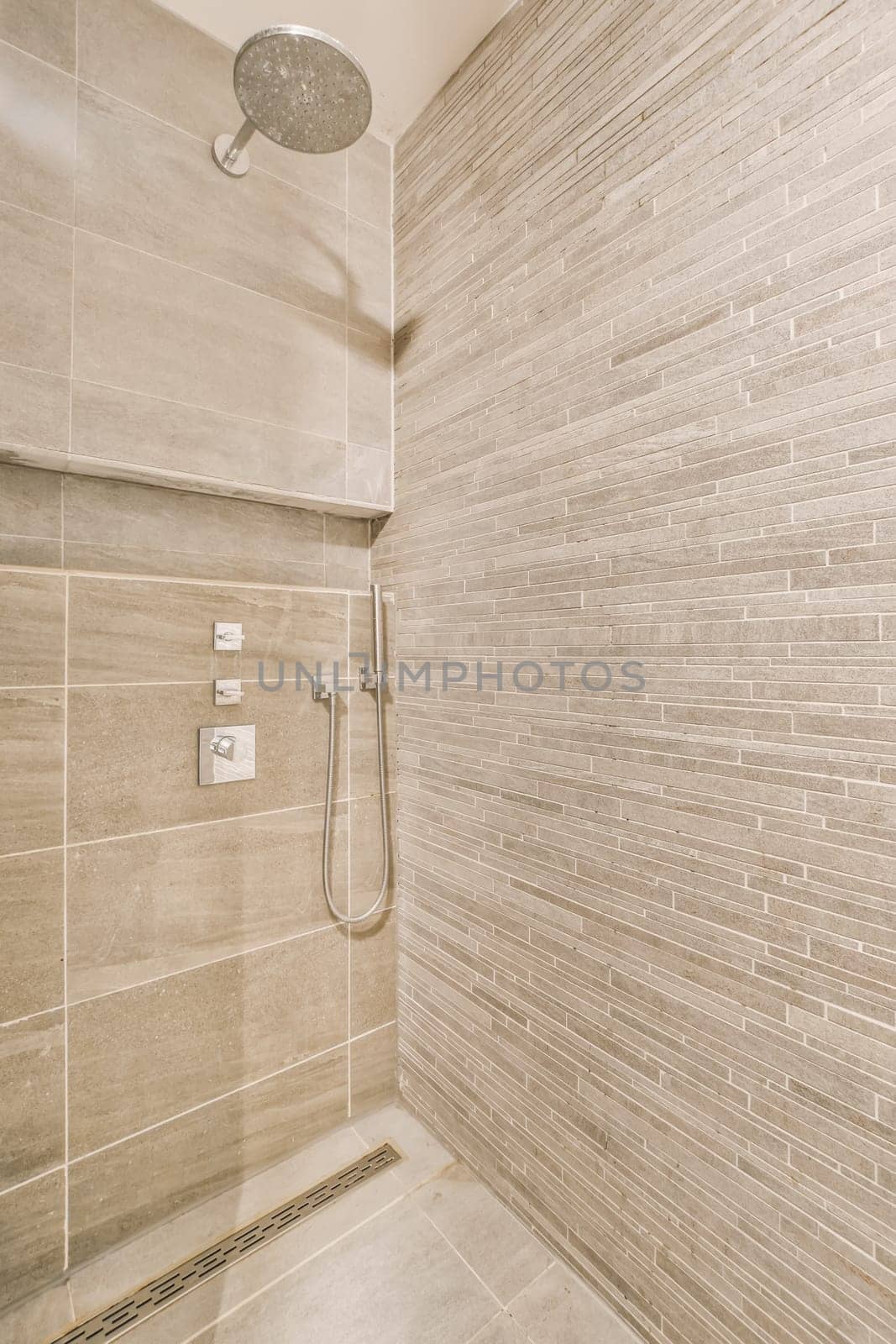 a bathroom with a shower and a tiled wall by casamedia