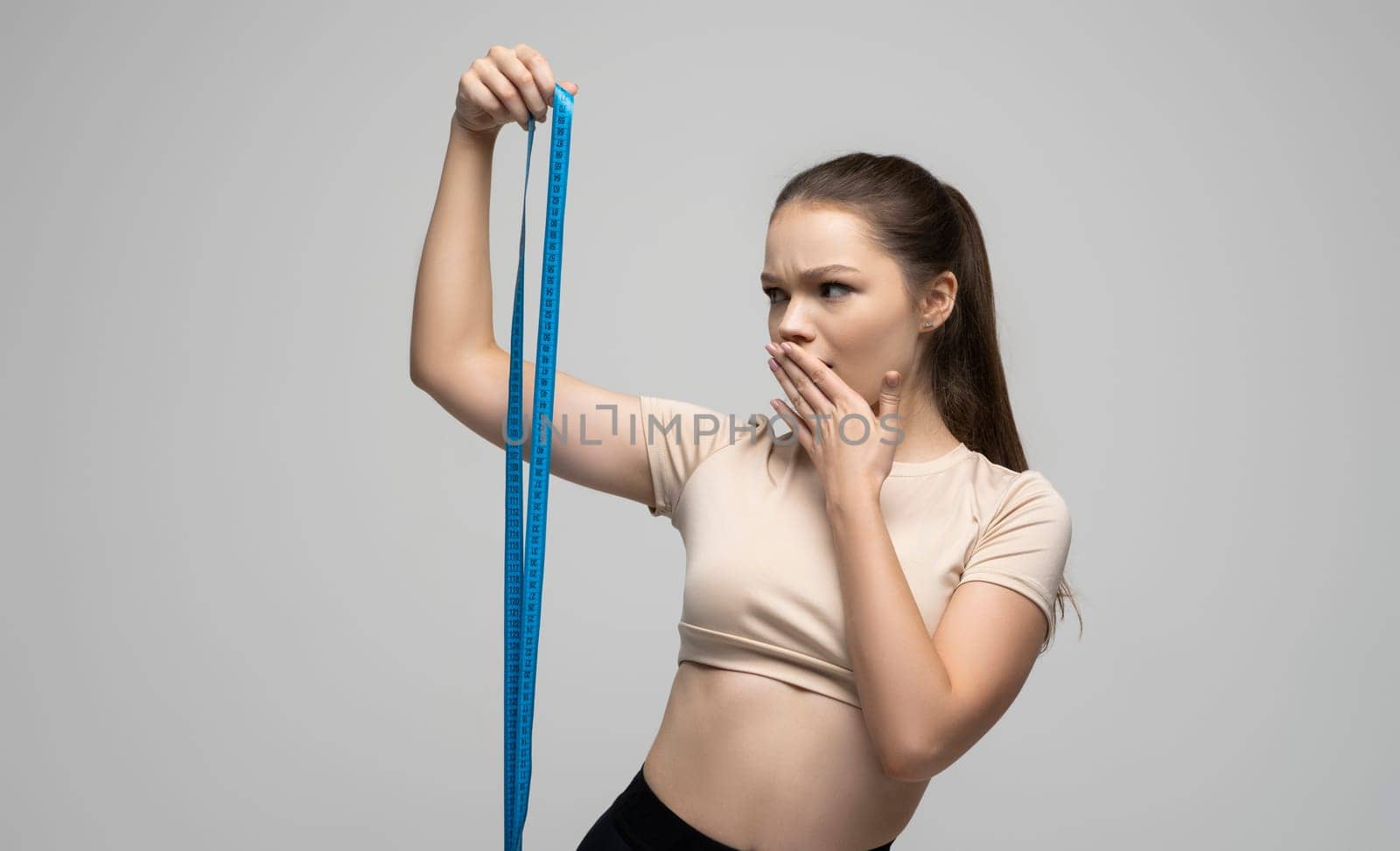 Confused sports woman, girl measuring her body after training in the gym. Fitness, weight loss and healthy lifestyles concept. by vovsht