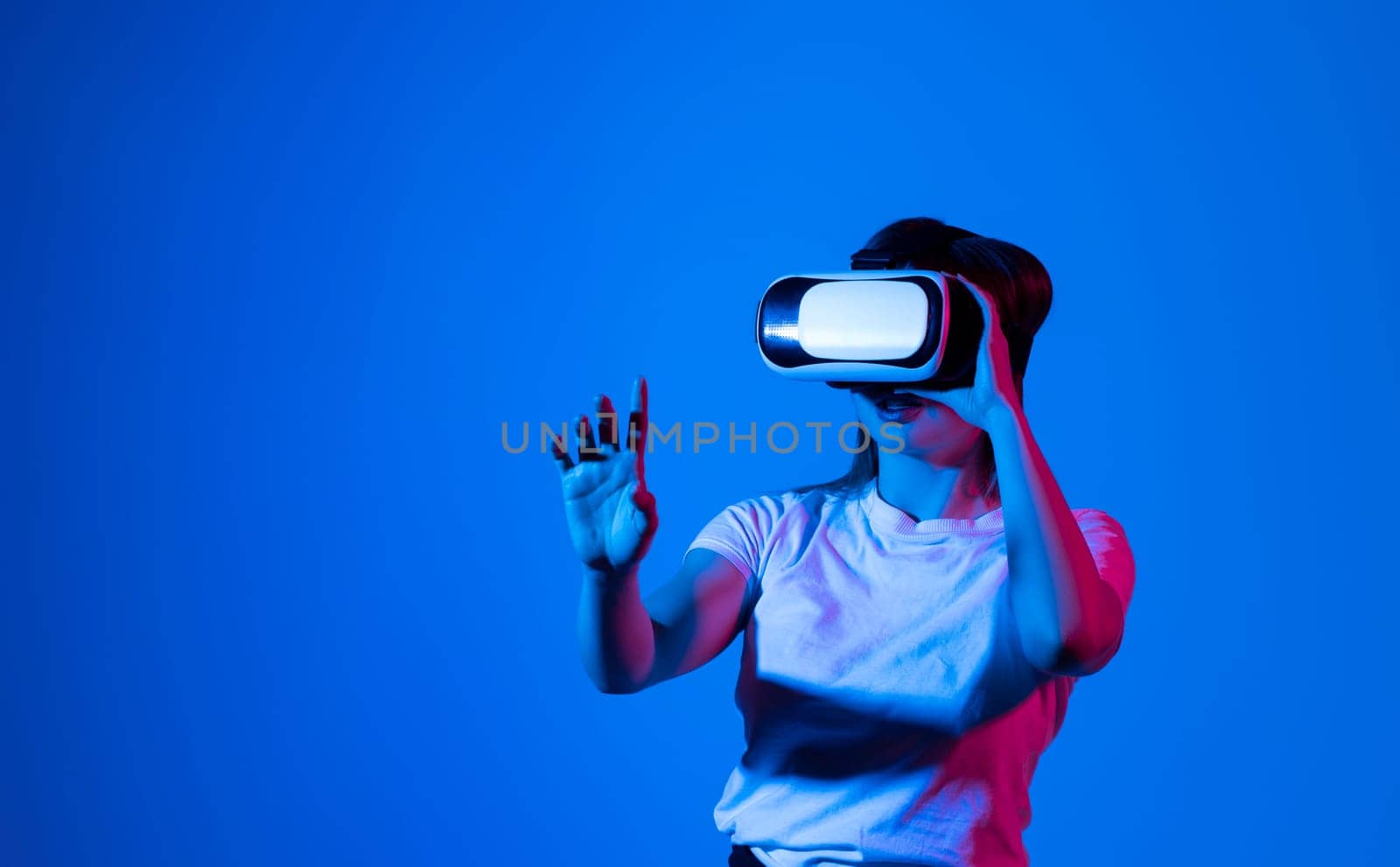 Woman in white shirt wearing VR glassess, VR set equipment for exploring a metaverse. Concept of metaverse, virtual reality, future, technology and internet. by vovsht