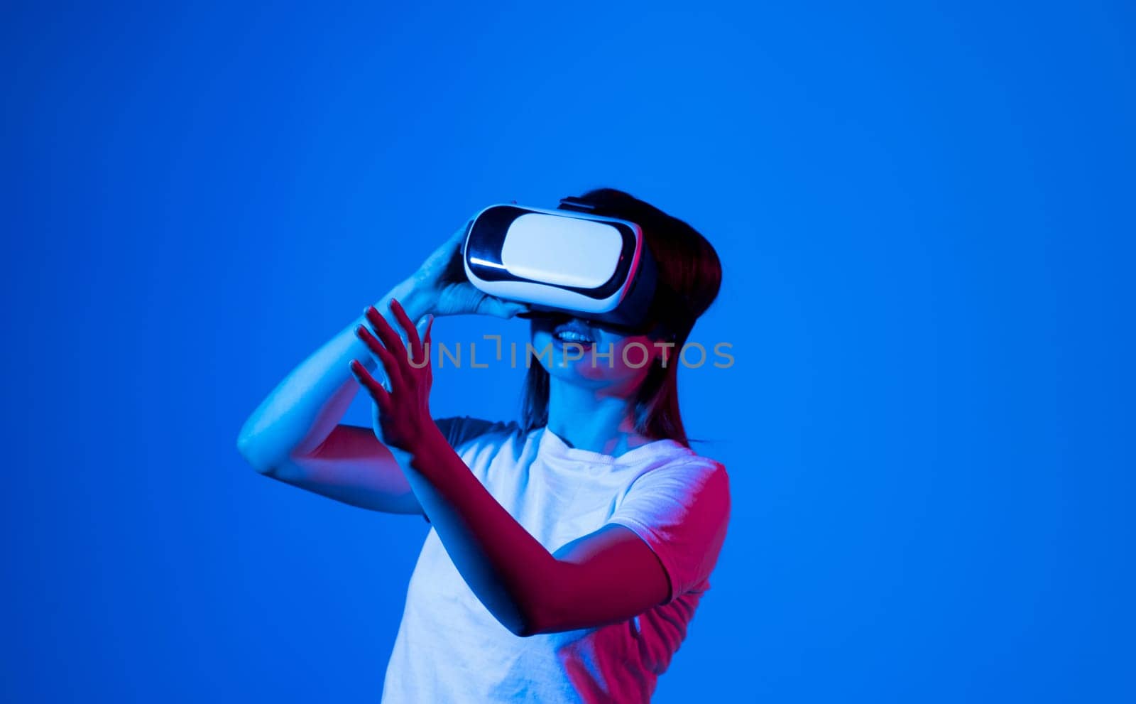 Brunette woman in VR glasses. Confident young woman in virtual reality headset pointing in the air while working in studio. by vovsht