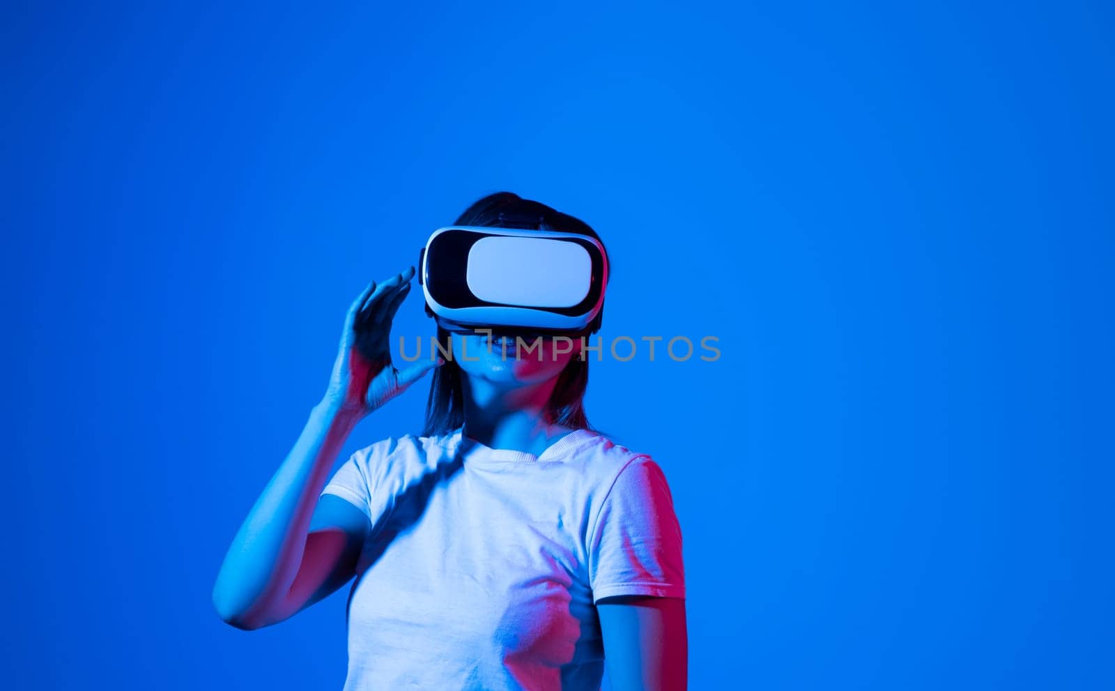 Brunette woman in white shirt wearing VR glassess, VR headset equipment for exploring a metaverse with a friends