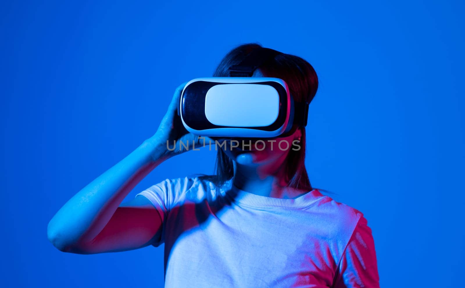 Brunette woman getting experience in metaverse using VR headset glasses. Exploring a cyberspace via virtual reality. by vovsht