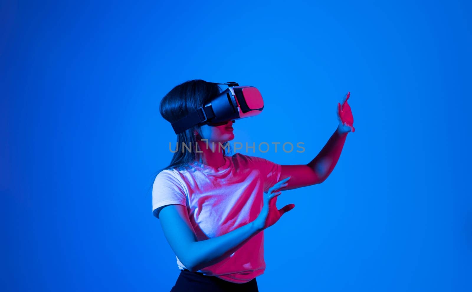 Woman wearing a VR headset and interacting with virtual reality. Simulation, future technology, AR and metaverse concept. by vovsht
