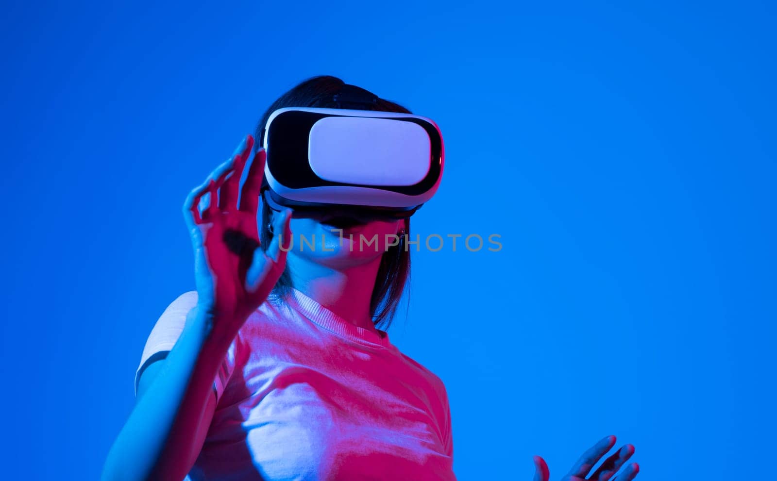 Woman in white shirt wearing VR glassess, VR set equipment for exploring a metaverse. Girl wearing a VR headset and interacting with virtual reality. Simulation, AR and metaverse concept