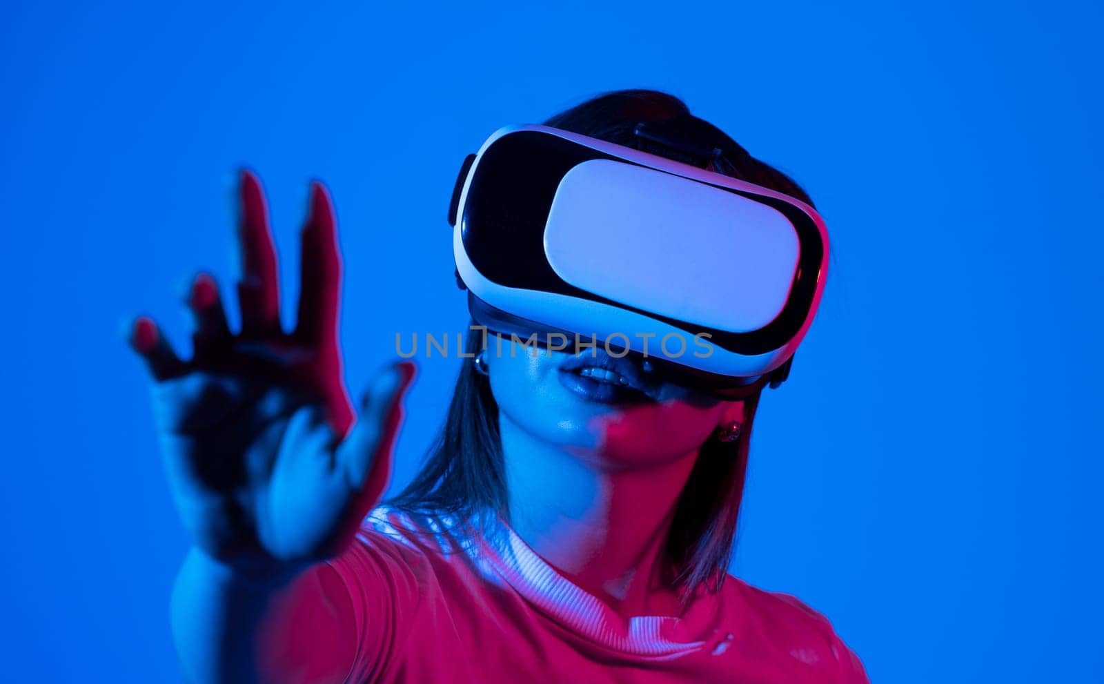 Brunette woman wearing VR virtual reality headset touching air during the VR on Metaverse experience. Technology, Video Game and Metaverse Concept. by vovsht