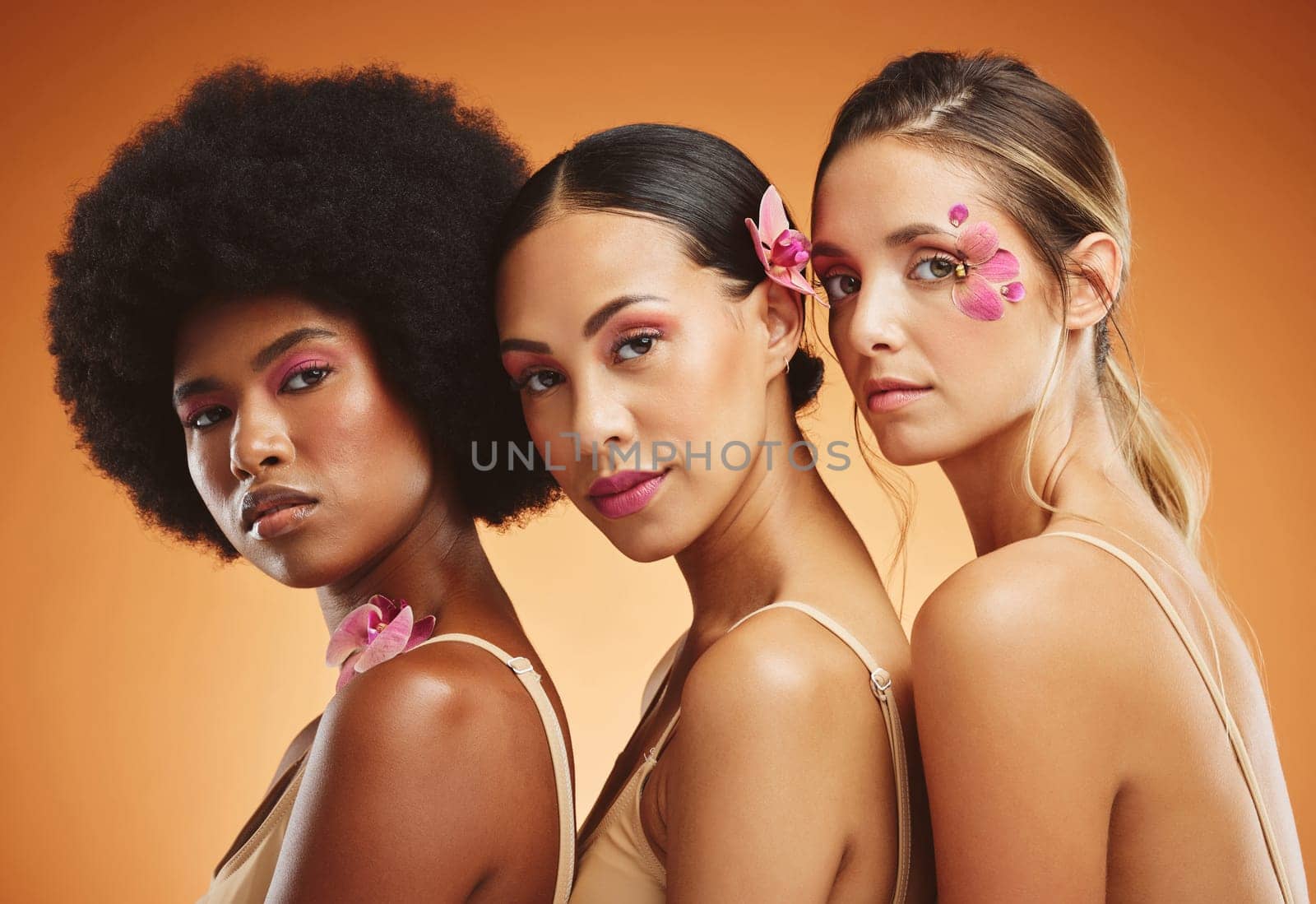 Skincare, flowers and beauty portrait of women in studio for feminism, woman empowerment and cosmetics. Diversity, face and group of beautiful natural models with floral standing by orange background.