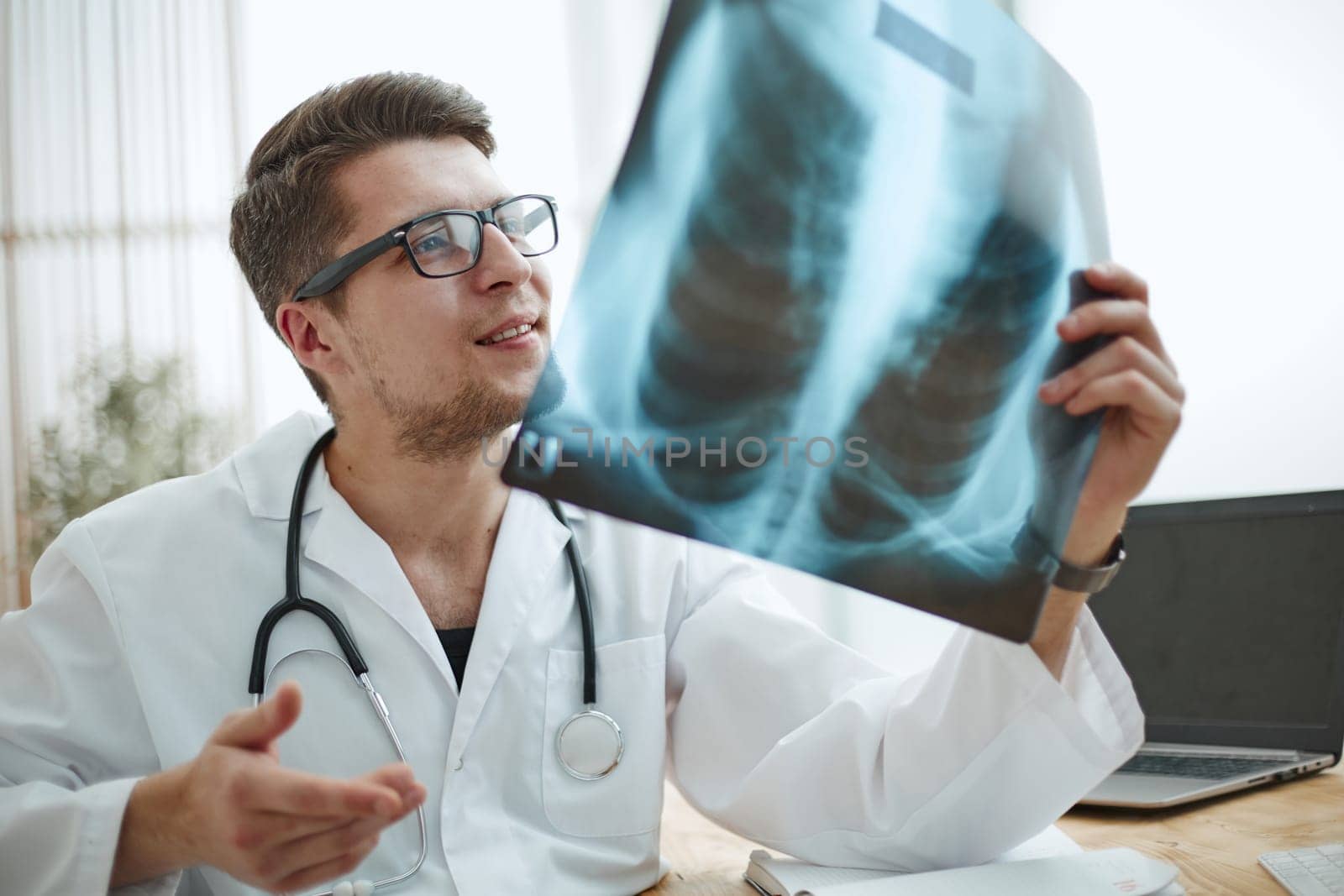 Male doctor in glass radiologist examines x-rays in a medical office.