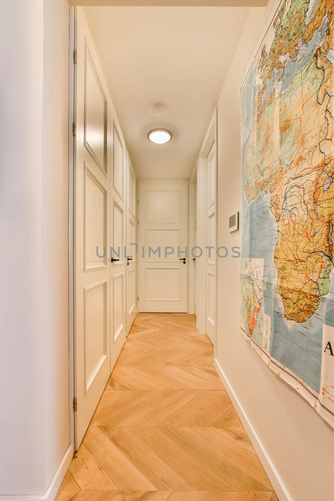 a map hanging on the wall in a long hallway with hardwood flooring and white trim around the doorways