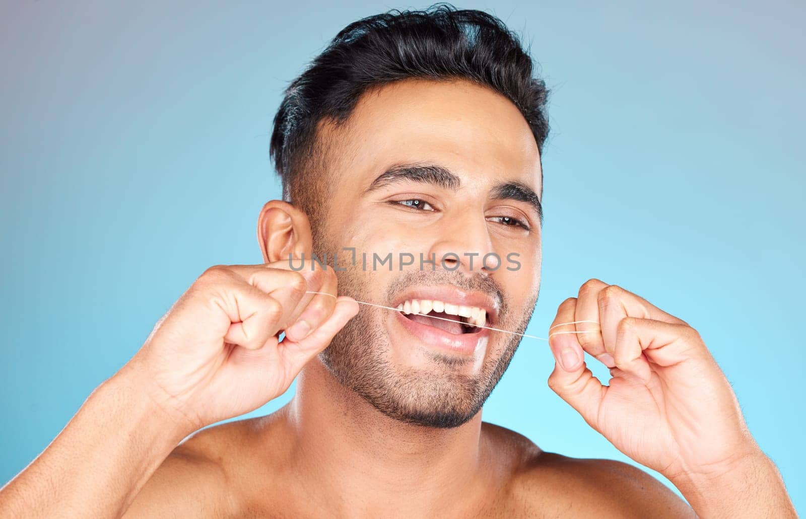 Floss, Mexican man and dental health for smile, fresh breath and after brushing teeth against blue studio background. Oral health, Latino male and string to clean mouth, hygiene and morning routine