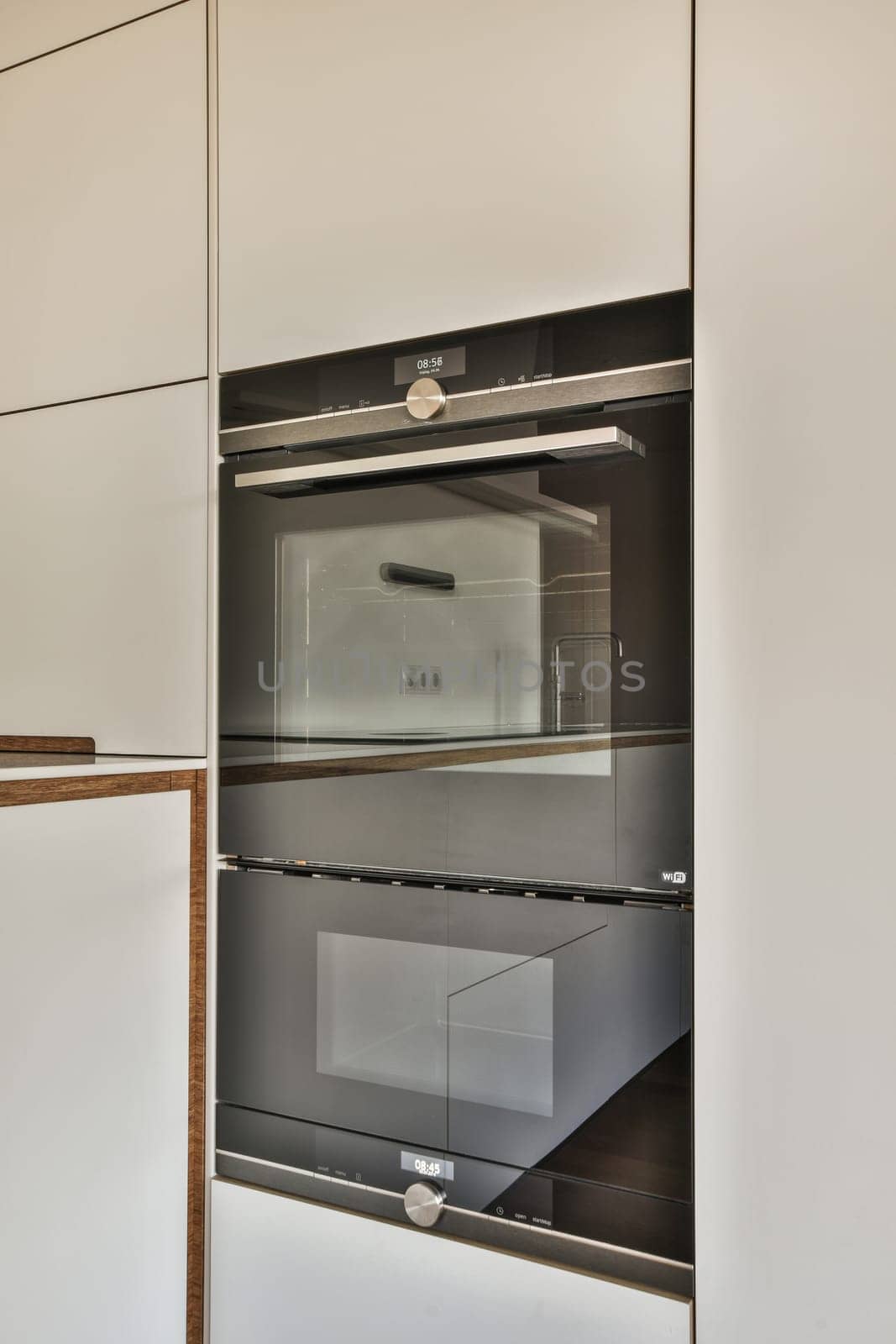 the inside of an oven in a kitchen with white cabinets and wood trims on the door, which is open