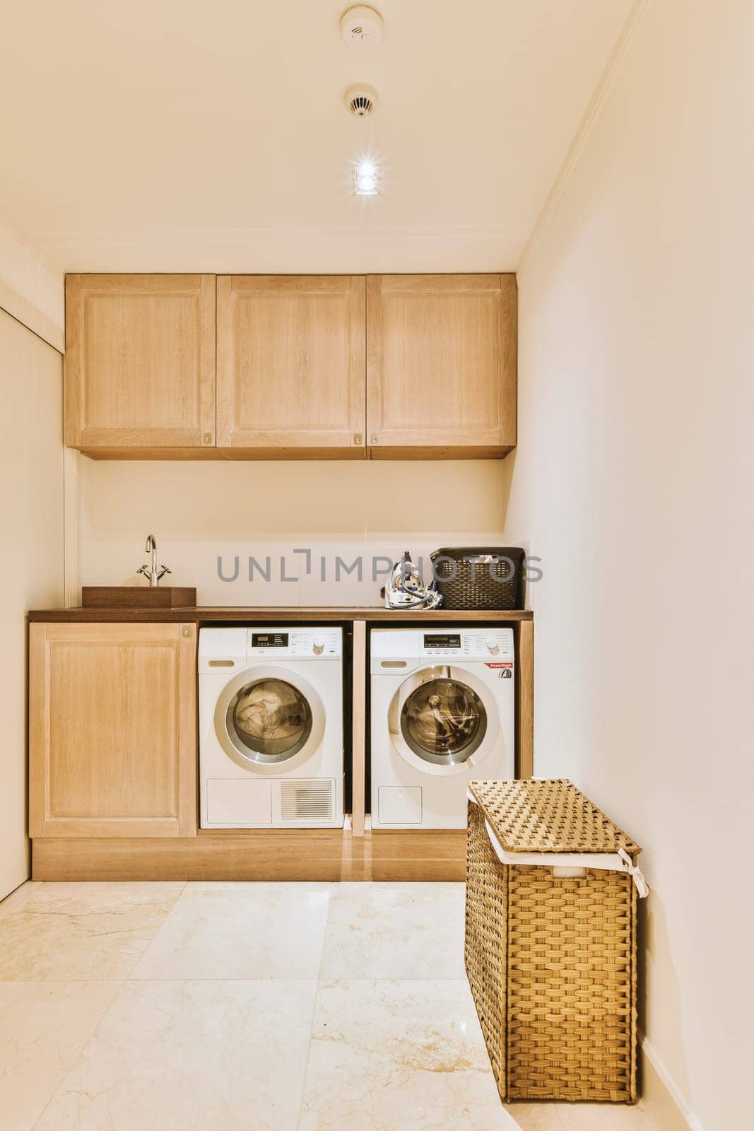 a small laundry room with washers and dryer in the corner on the left is a basket that has been used