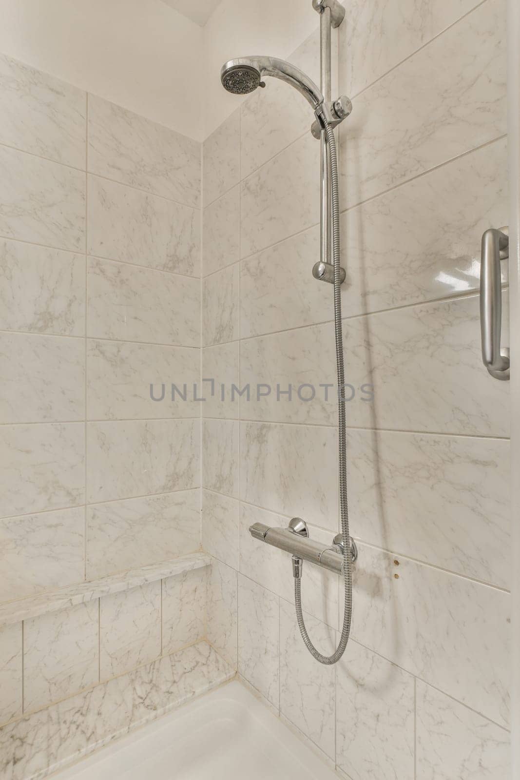 a bathroom with marble walls and white tiles on the wall, including a shower head in the tub is next to the bathtub