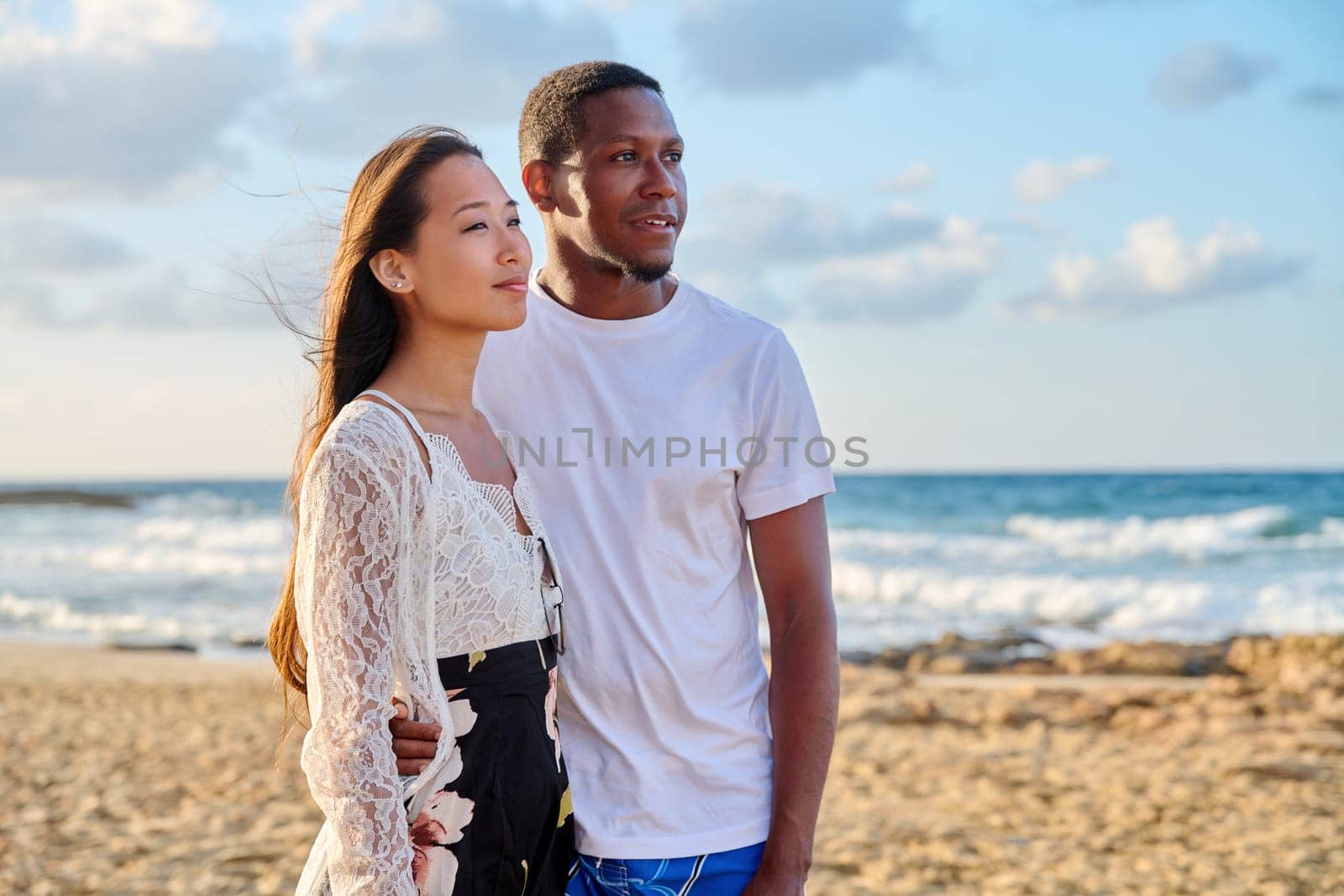 Young couple in love on the beach together. Multiethnic couple, asian woman and african american man. Love, honeymoon, relationship, lifestyle, togetherness, happiness, dating, multicultural family concept