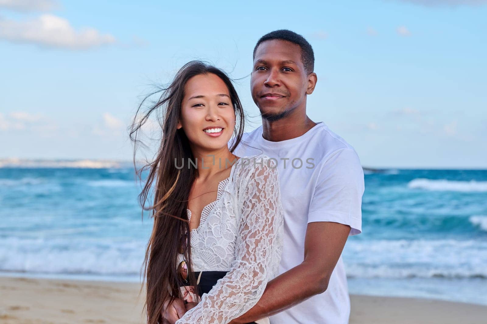 Beautiful young couple in love on beach. Portrait of Asian woman and African American man embracing. Multicultural, multiethnic family, relationships, togetherness, lifestyle, sea nature vacation