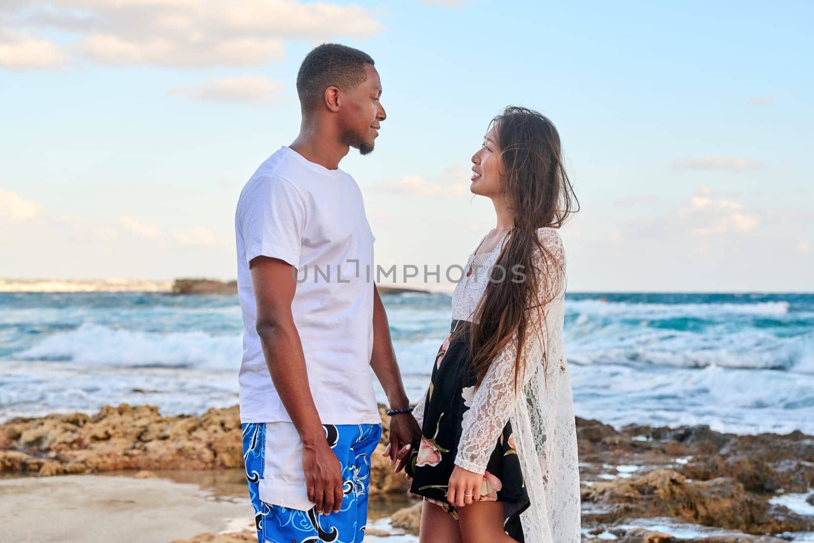Beautiful young couple in love on beach. Portrait of Asian woman and African American man looking at each other. Multicultural, multiethnic family, relationships, togetherness, lifestyle, sea nature vacation