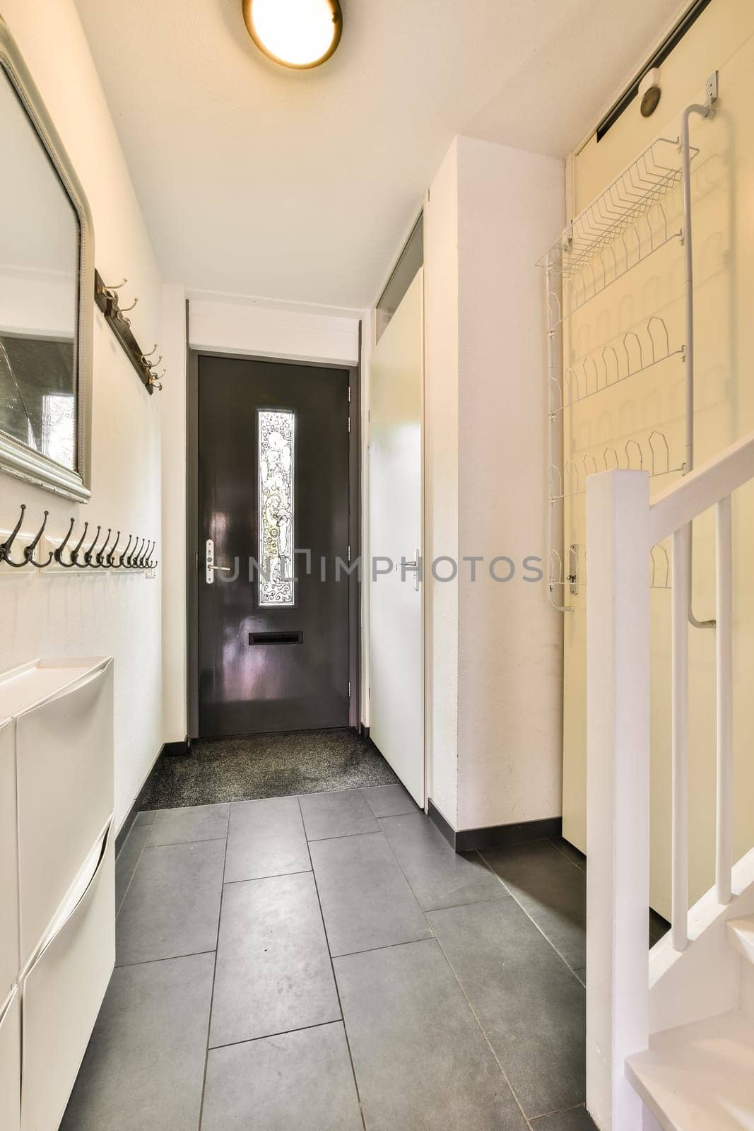 a long hallway with white walls and a black door by casamedia