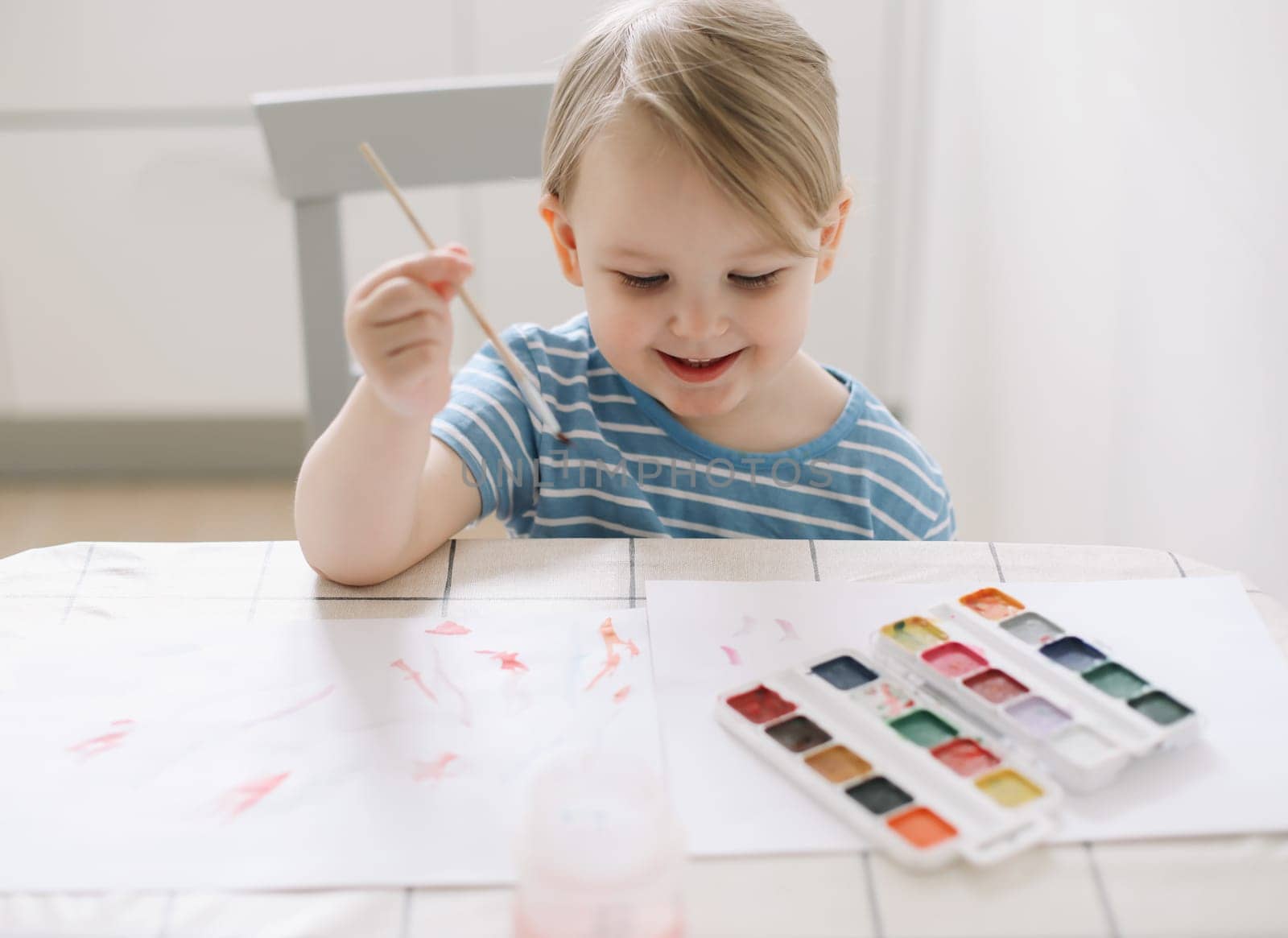 Small preschooler girl sit at desk painting, quarantine, homeschooling concept
