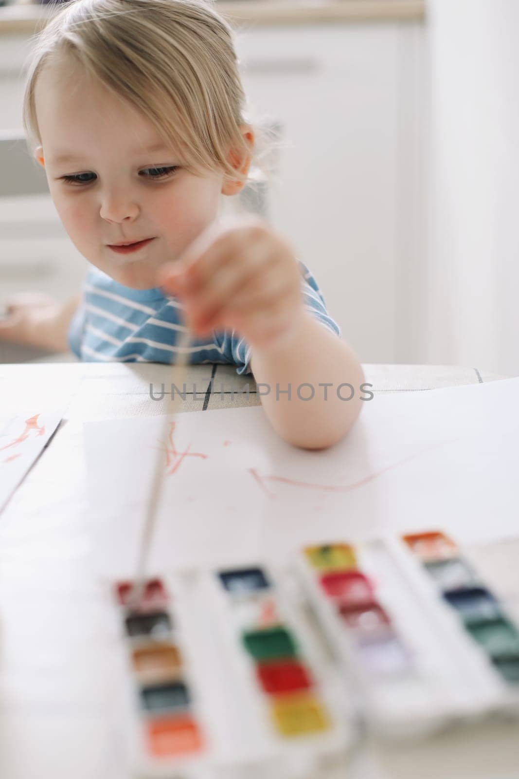 Child painting and drawing with watercolor paint at white table. Development of creative potential in children. quarantine, homeschooling concept by paralisart