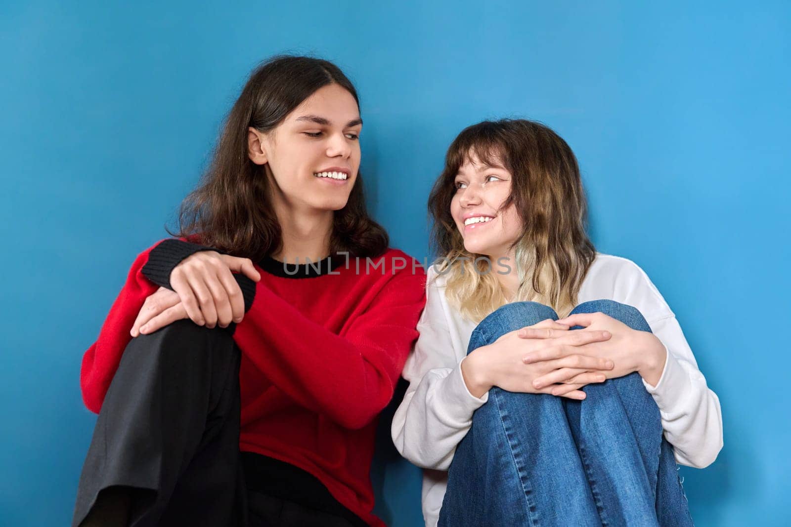 Portrait of a teenage couple of young students on a blue background. Youth, color, lifestyle, friendship, young people concept