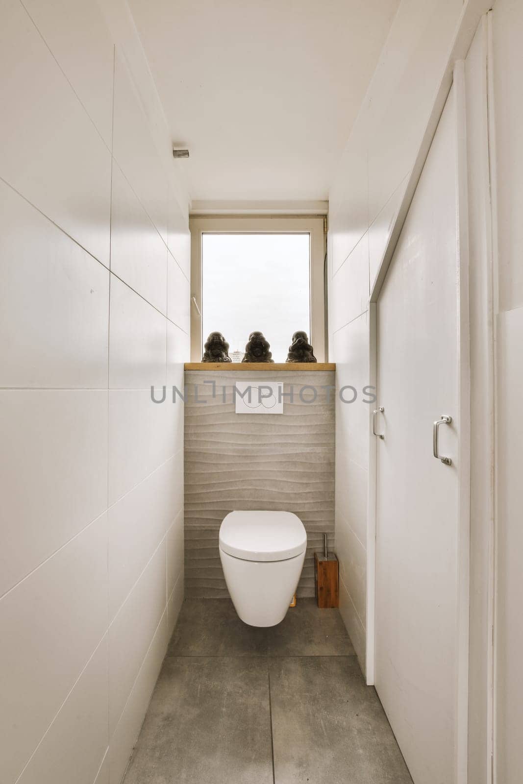 a toilet in the corner of a bathroom with two people sitting on the window ledge above it and looking out