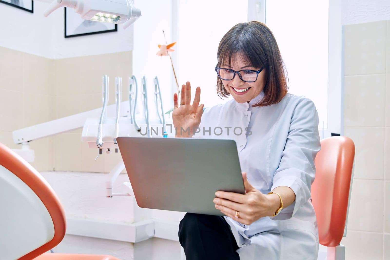 Online consultation, doctor help in clinic using laptop. Female dentist talking looking in laptop in dental office. Video conference, videocall, service, dentistry, medicine, technology concept