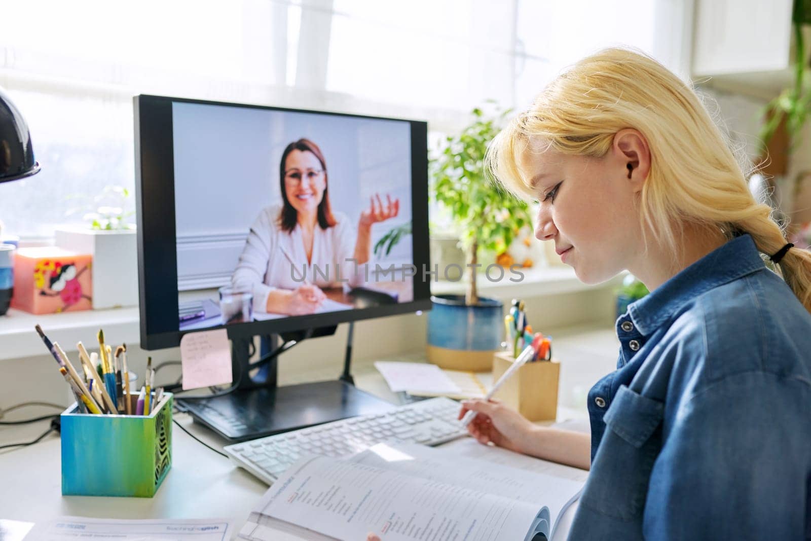 Teenage girl studying at home online using computer by VH-studio