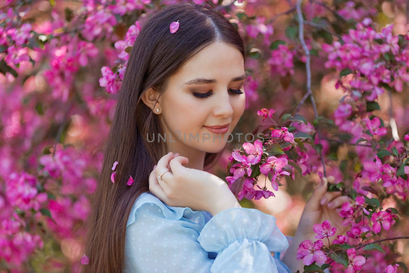 Portrait of girl is standing near a blooming apple tree by Zakharova