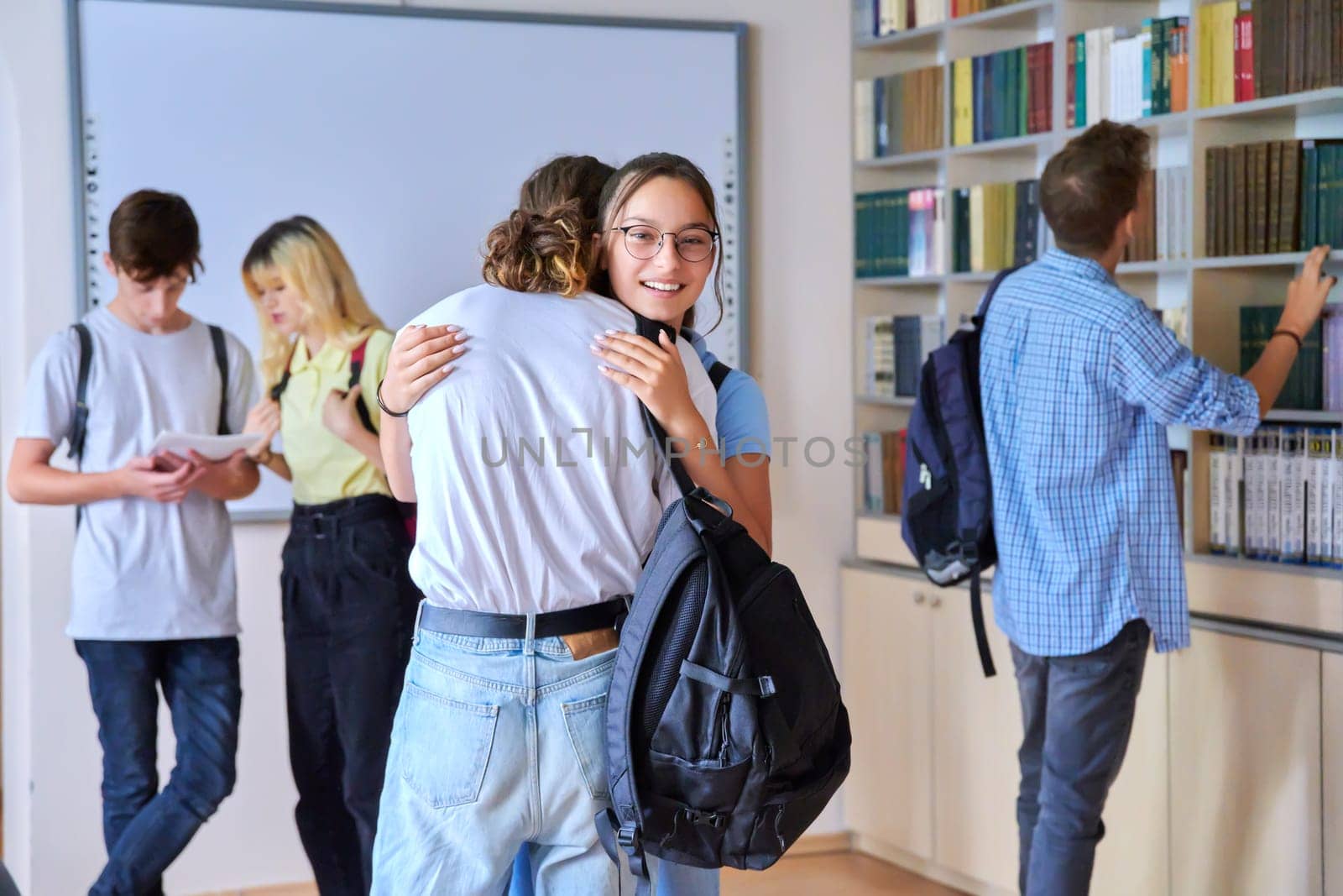 Group of teenagers guys and girls are welcome, meeting, smiling, rejoicing inside school by VH-studio