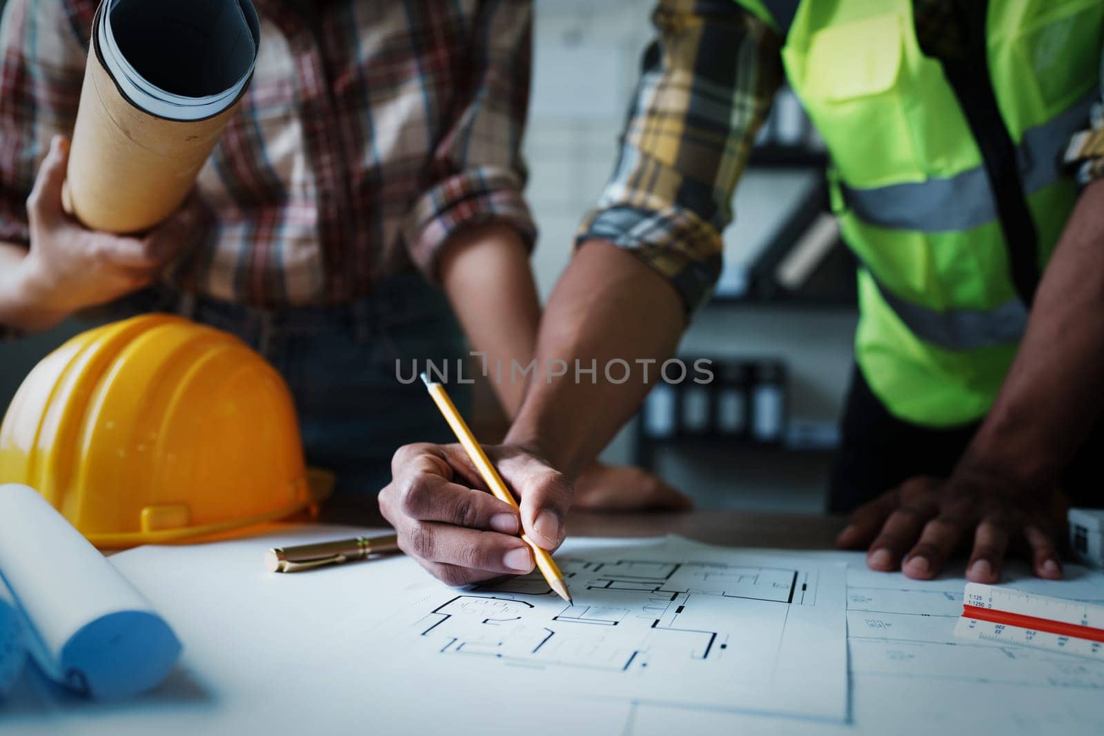 Engineers are consulting the team to design an architectural structure for clients with blueprints and building models to work at office by Manastrong