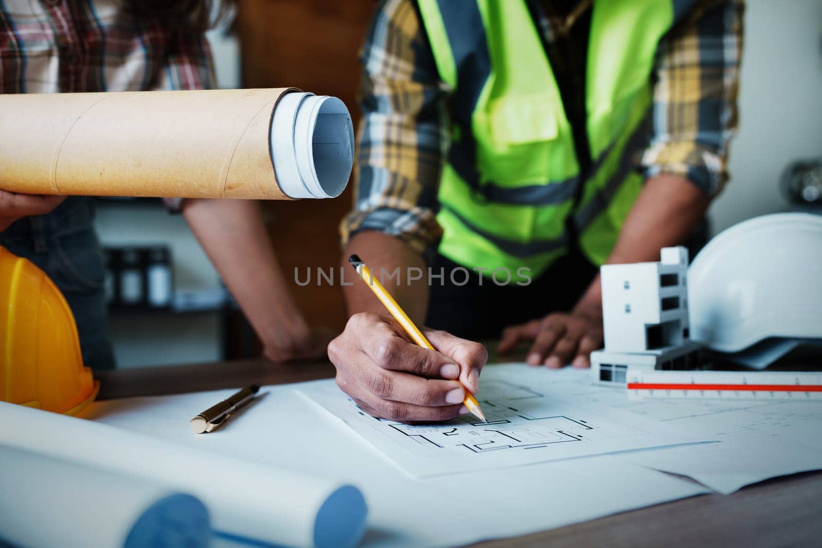 Engineers are consulting the team to design an architectural structure for clients with blueprints and building models to work at office.