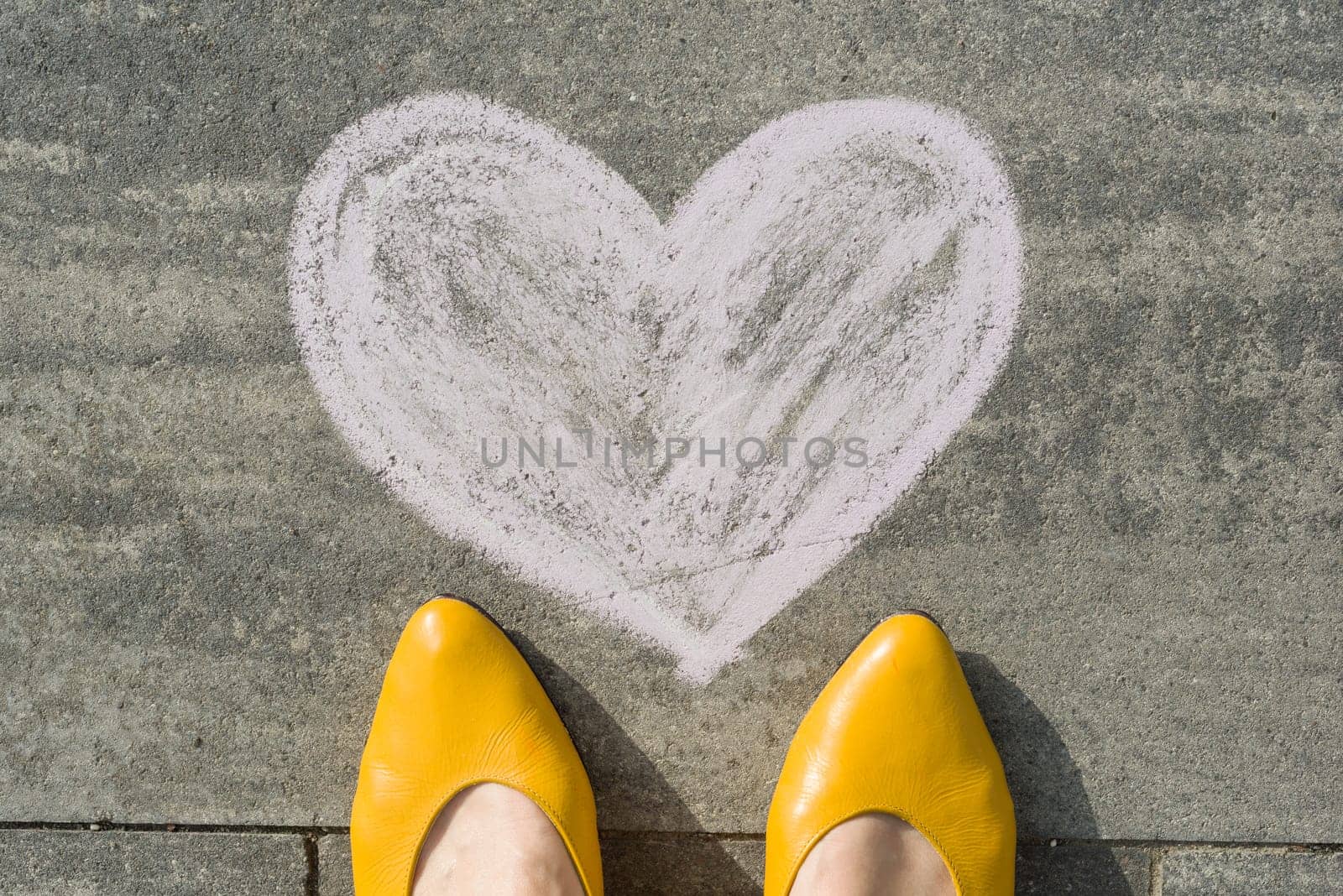 Female feet with symbol heart painted on the asphalt