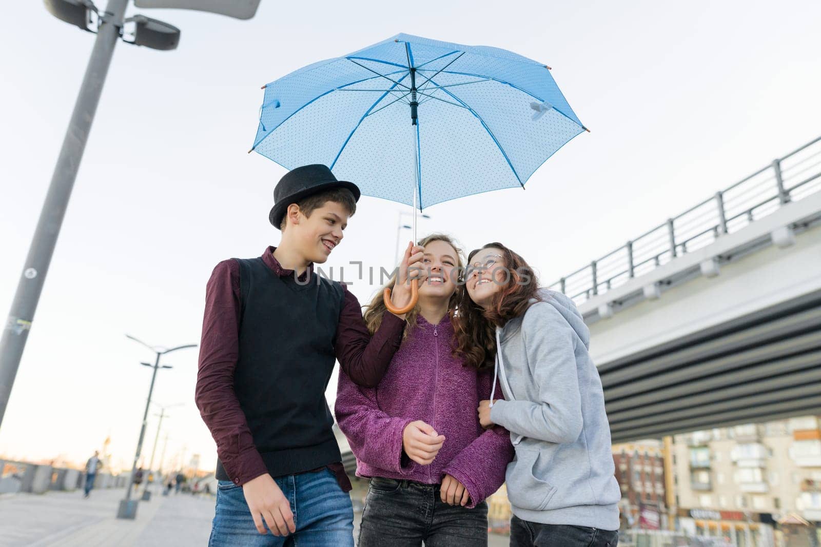 Teens boy and two girls talking and having fun outdoor, lifestyle of teenagers in the city