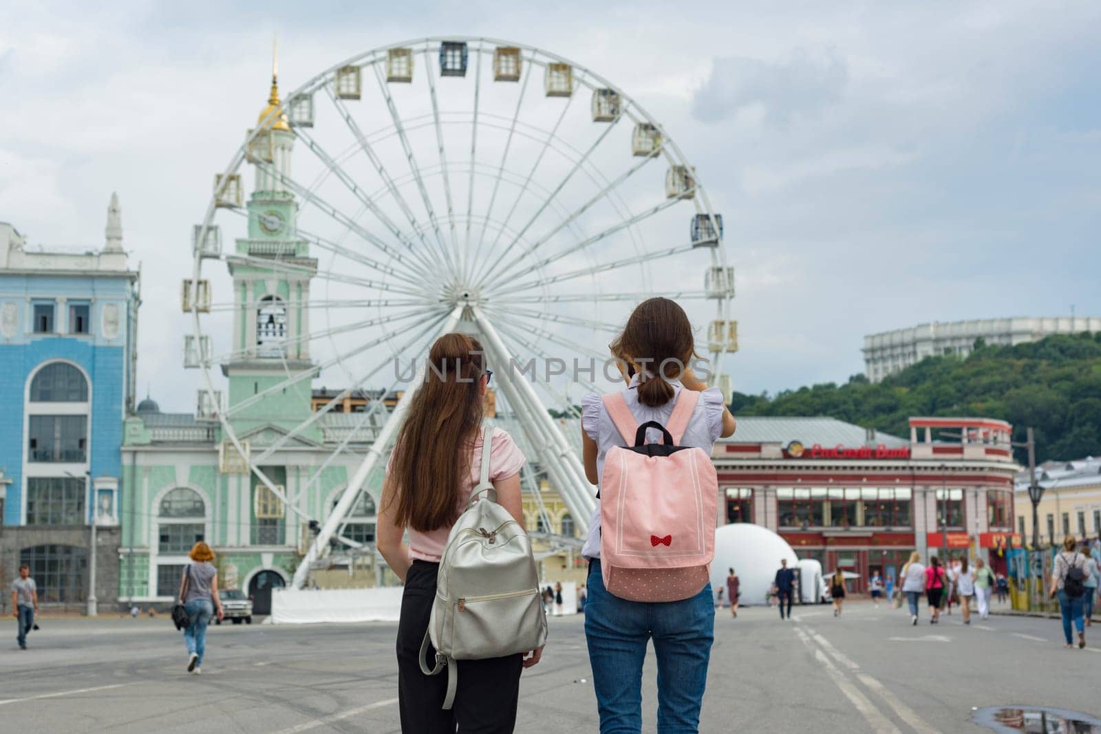 Kyiv UA, 19-07-2018. Young teenage girls are walking the streets of the city. Background Ferris wheel, square of the European city, view from the bac.