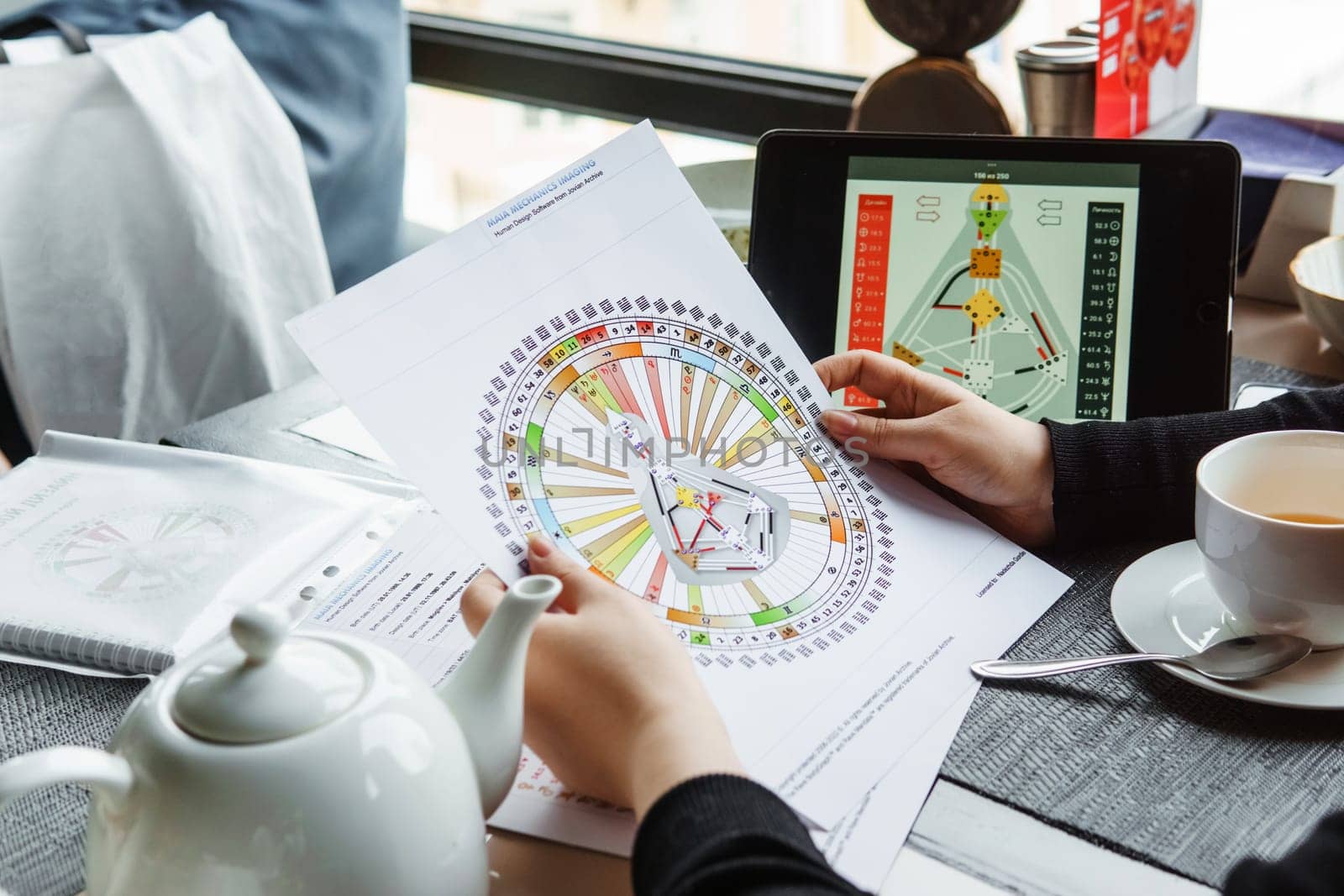 TVER, RUSSIA - FEBRUARY 12, 2023: A woman at the table is studying a rave mandala by human design. Rave mandala on the table close-up. The concept of esoteric teachings. by Annu1tochka