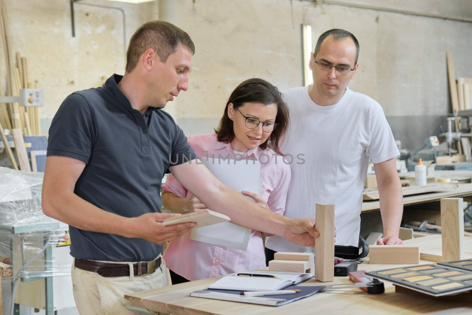 Group of people designer, client, carpenter, engineer choosing wooden products, working discussion, background carpentry workshop.