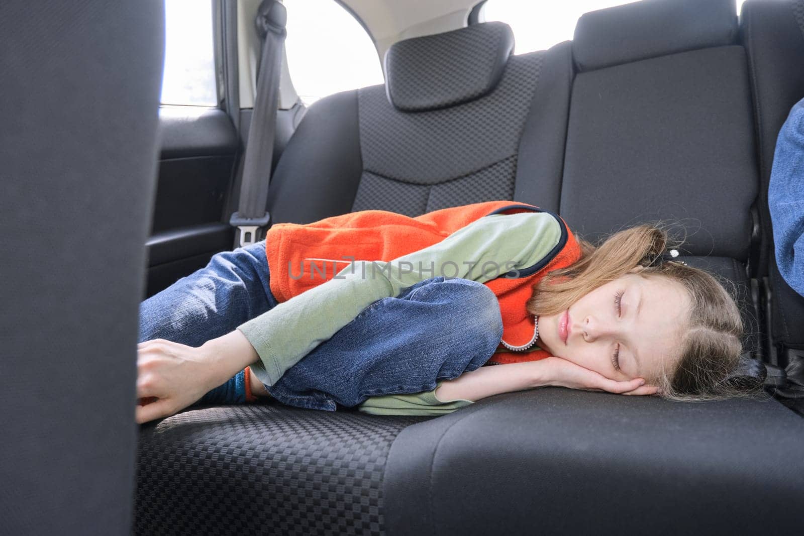 9 year old girl sleeping in car, child lying in the back seat of vehicle.