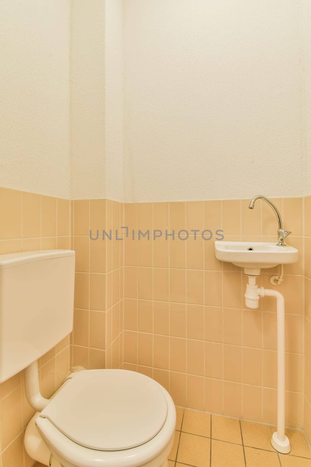 a white toilet and sink in a small bathroom with tile on the floor, walls and ceiling is painted beige