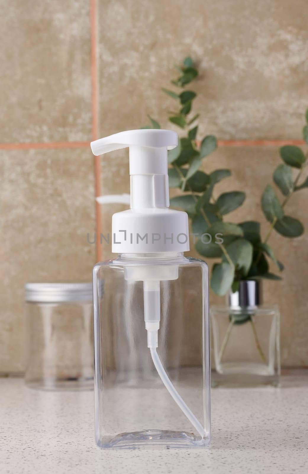 Transparent plastic container with a dispenser on the table. Bottle for liquid soap, shampoo by ndanko