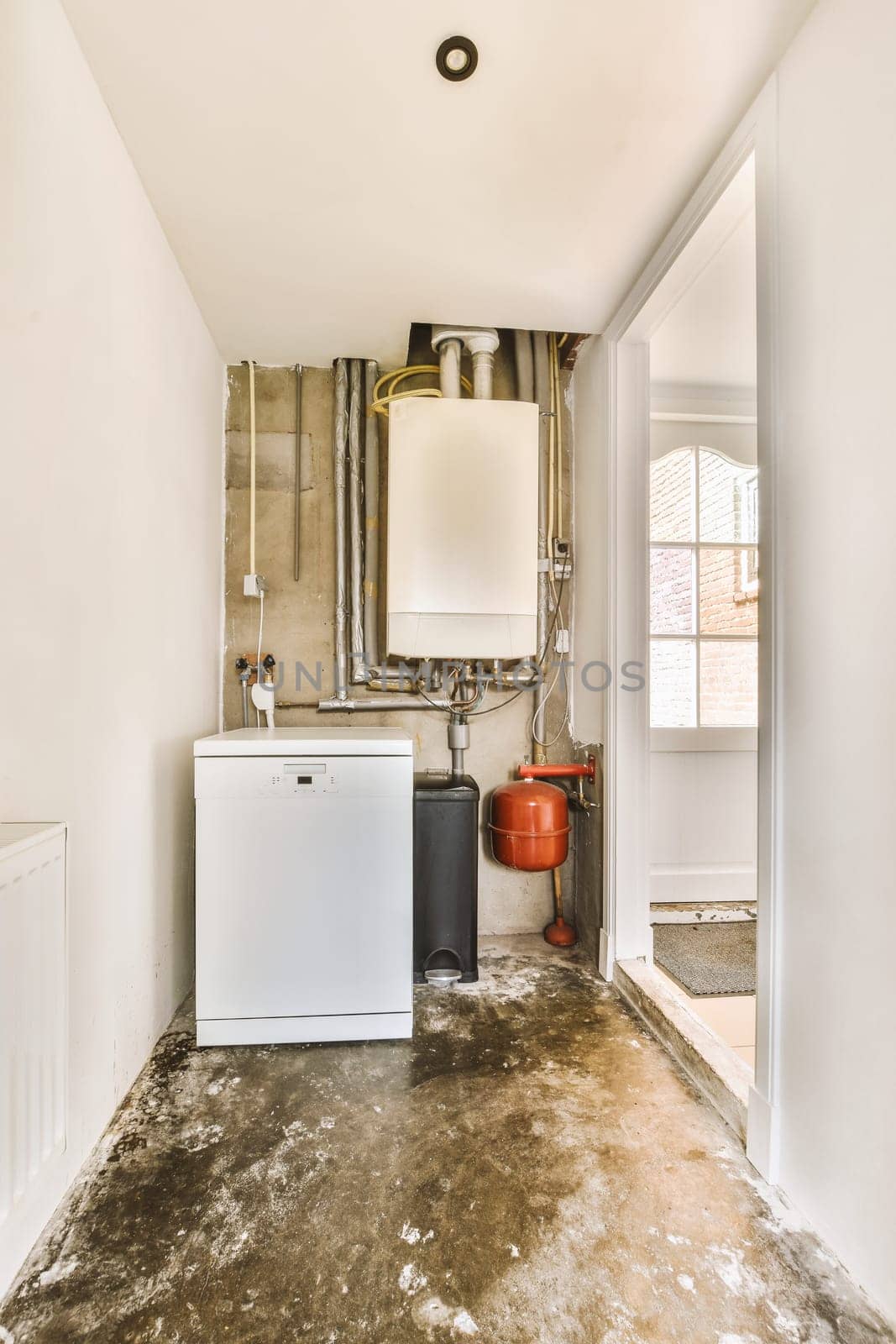 a small kitchen with a white refrigerator and exposed pipes by casamedia