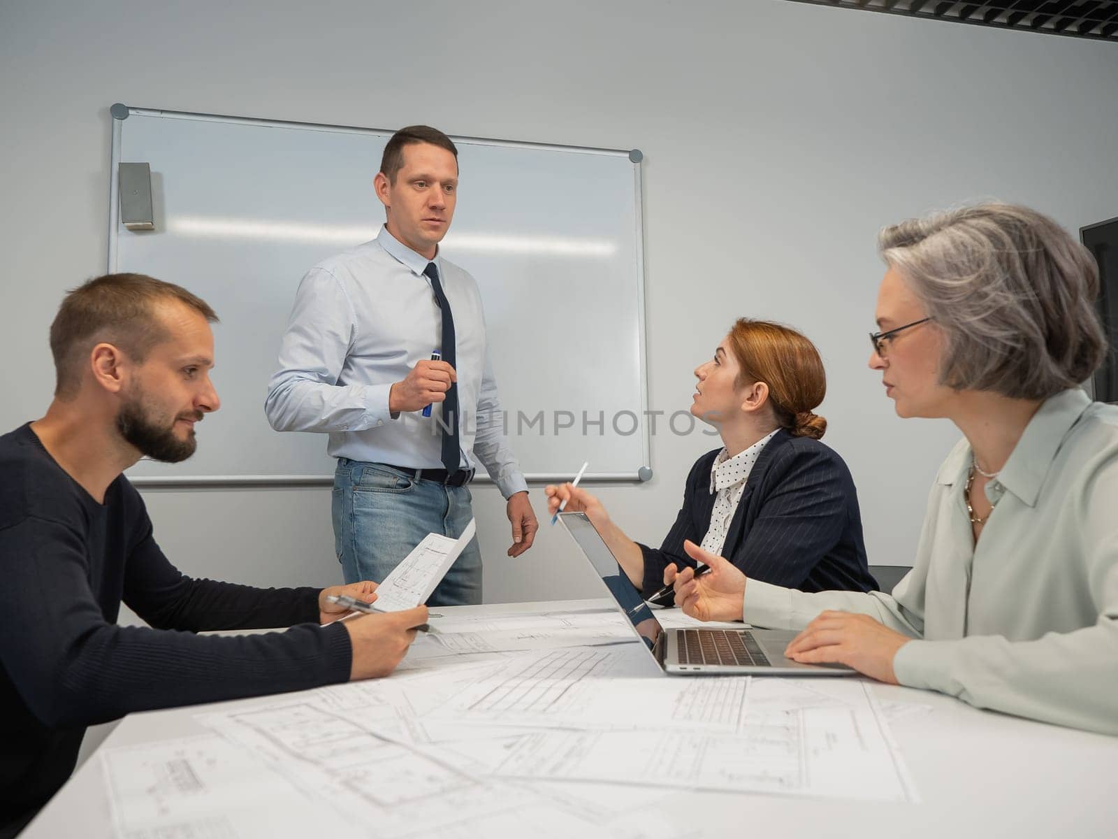 Caucasian man leading a presentation to colleagues at a white board