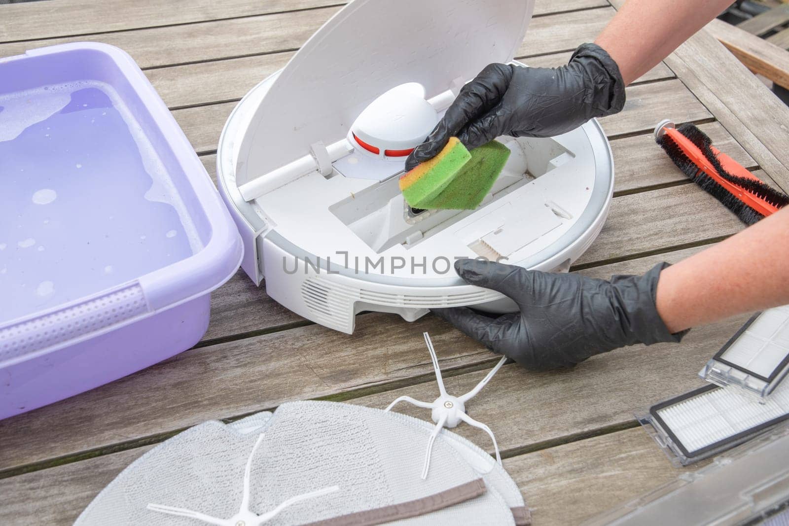 woman washing a trash can in a robot vacuum cleaner,planned maintenance of equipment for long-term use, High quality photo