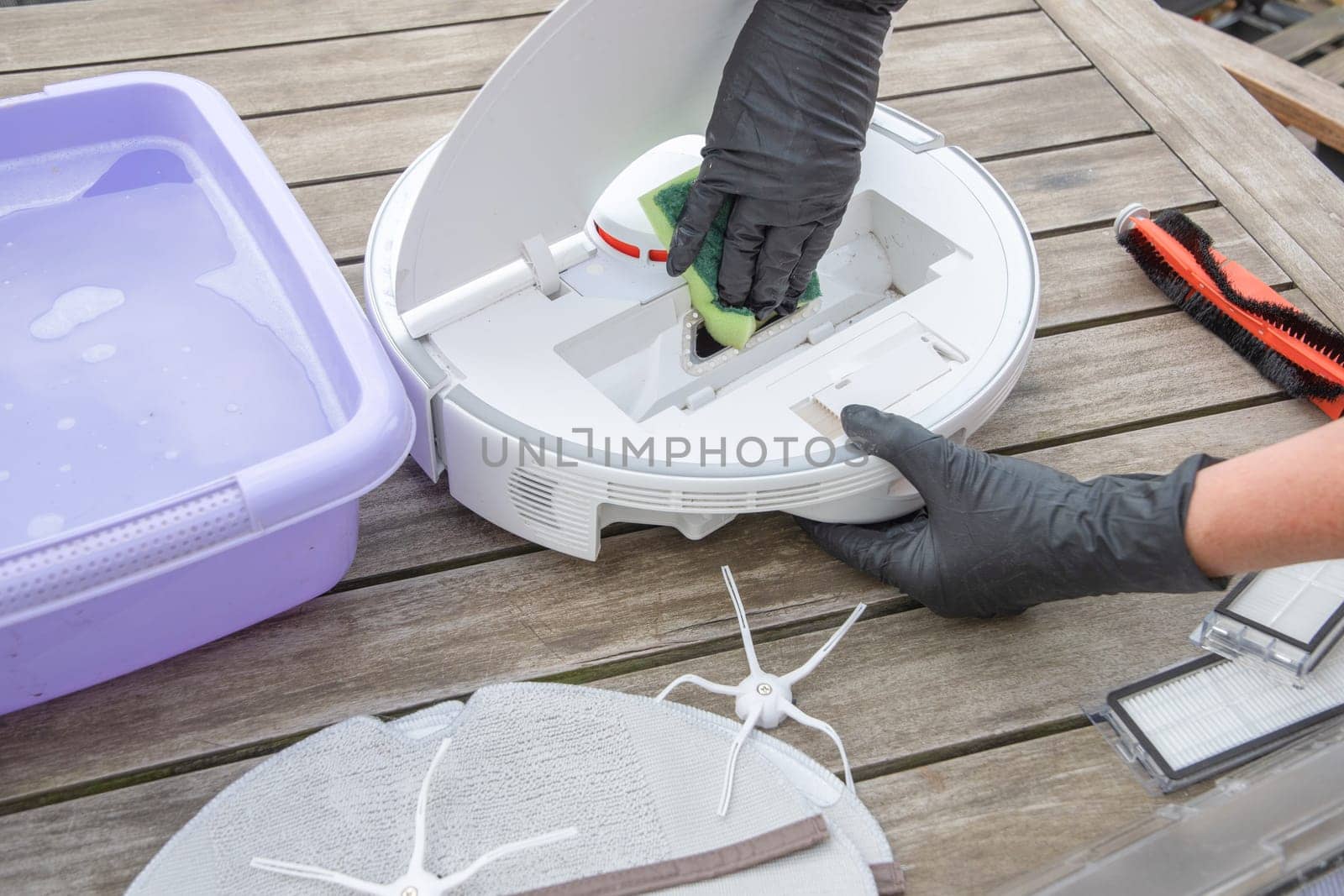 woman washing a trash can in a robot vacuum cleaner,planned maintenance of equipment for long-term use, High quality photo