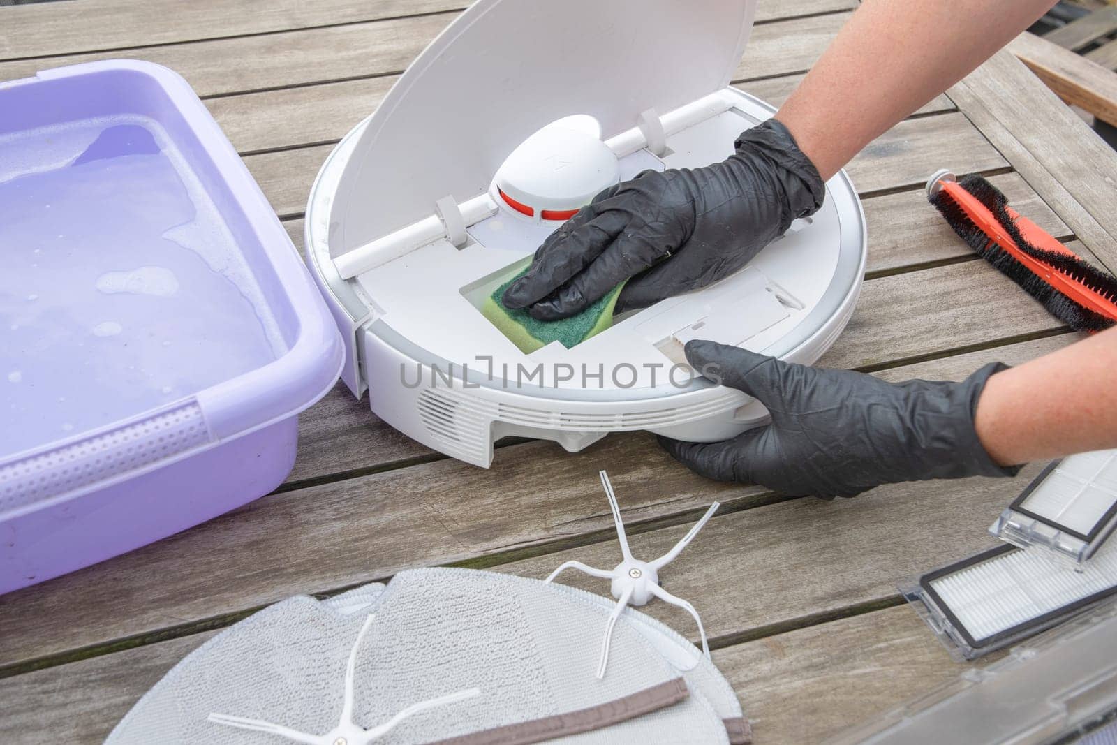 woman washing a trash can in a robot vacuum cleaner,planned maintenance of equipment for long-term use, High quality photo