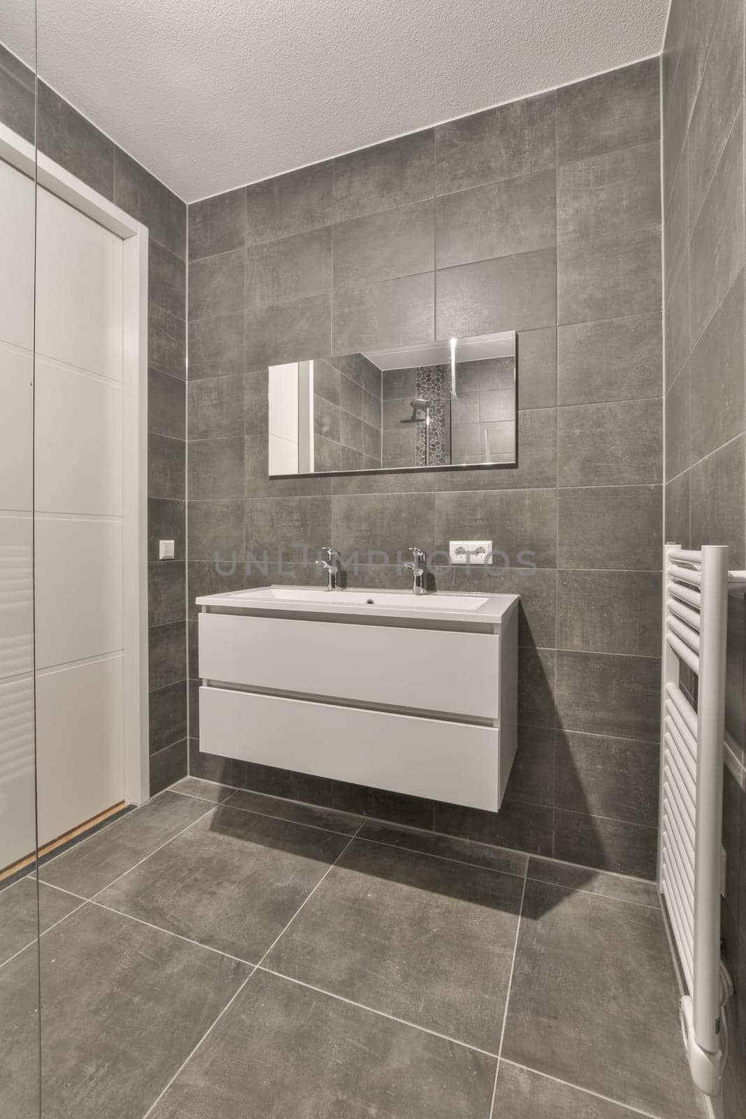 a modern bathroom with grey tiles and white fixtures on the walls, along with a large mirror in the corner