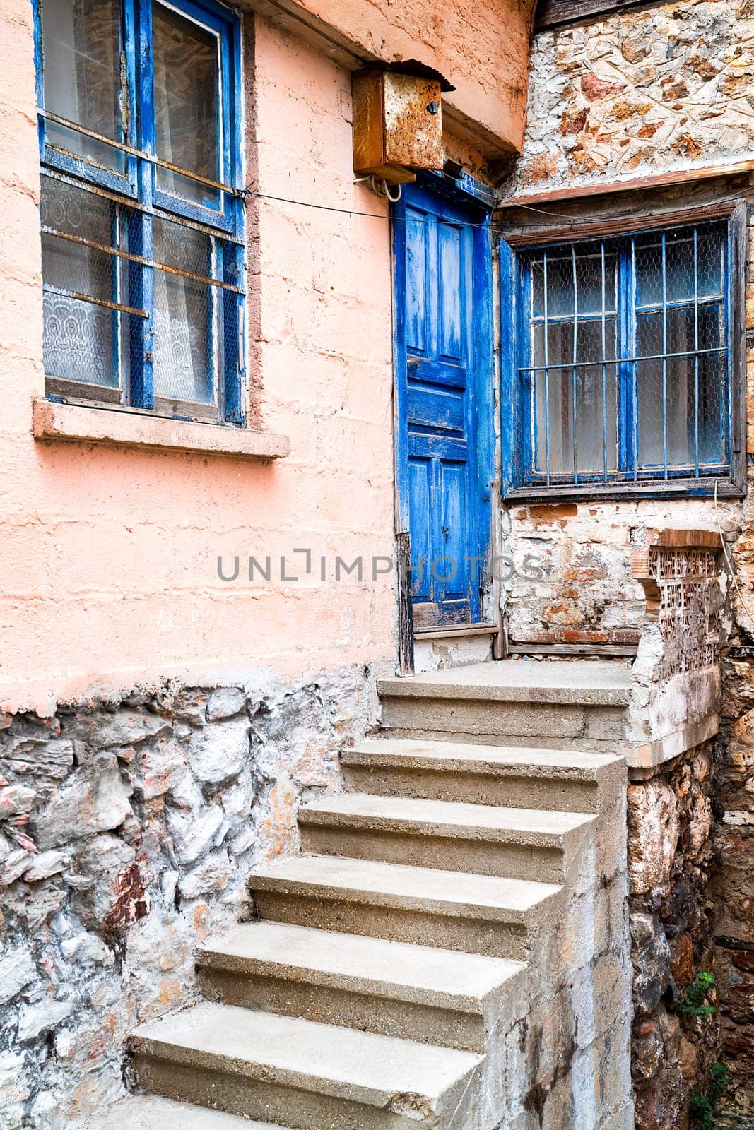Door and window painted blue colour on facade of old turkish village house, vertical frame