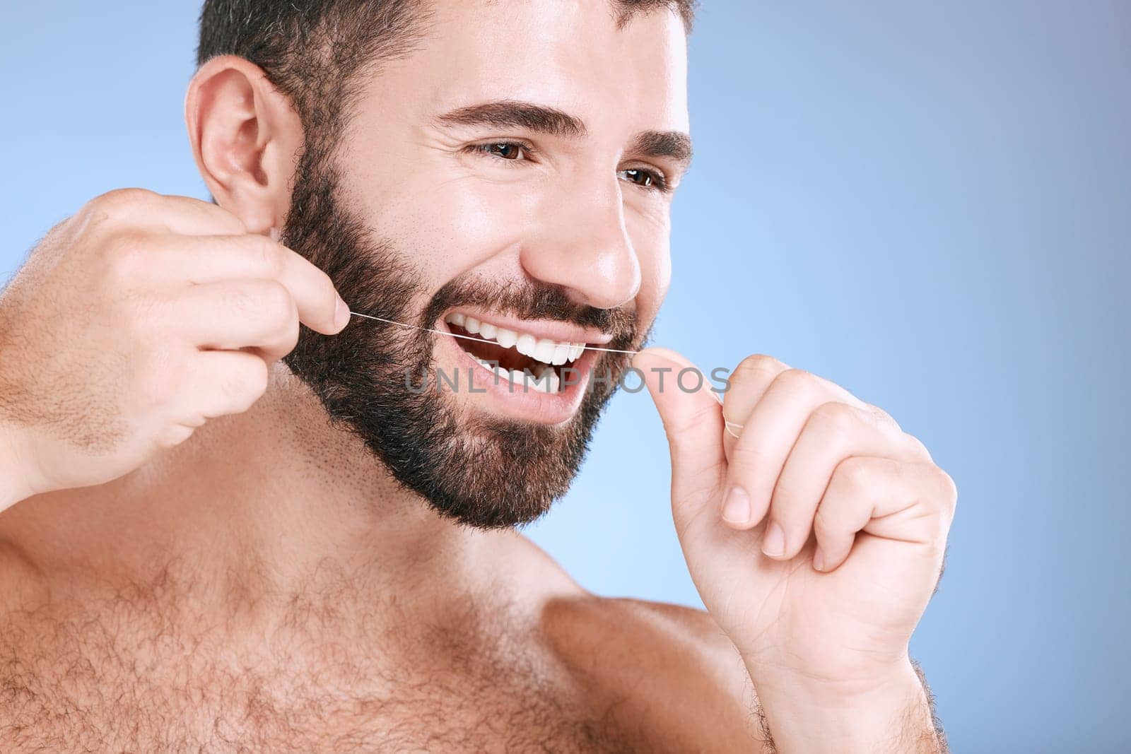 Dental, product or floss with a man in studio on a blue background with teeth hygiene for healthy gums. Dentist, healthcare and mouth with a young male oral cleaning to remove plague or gingivitis by YuriArcurs